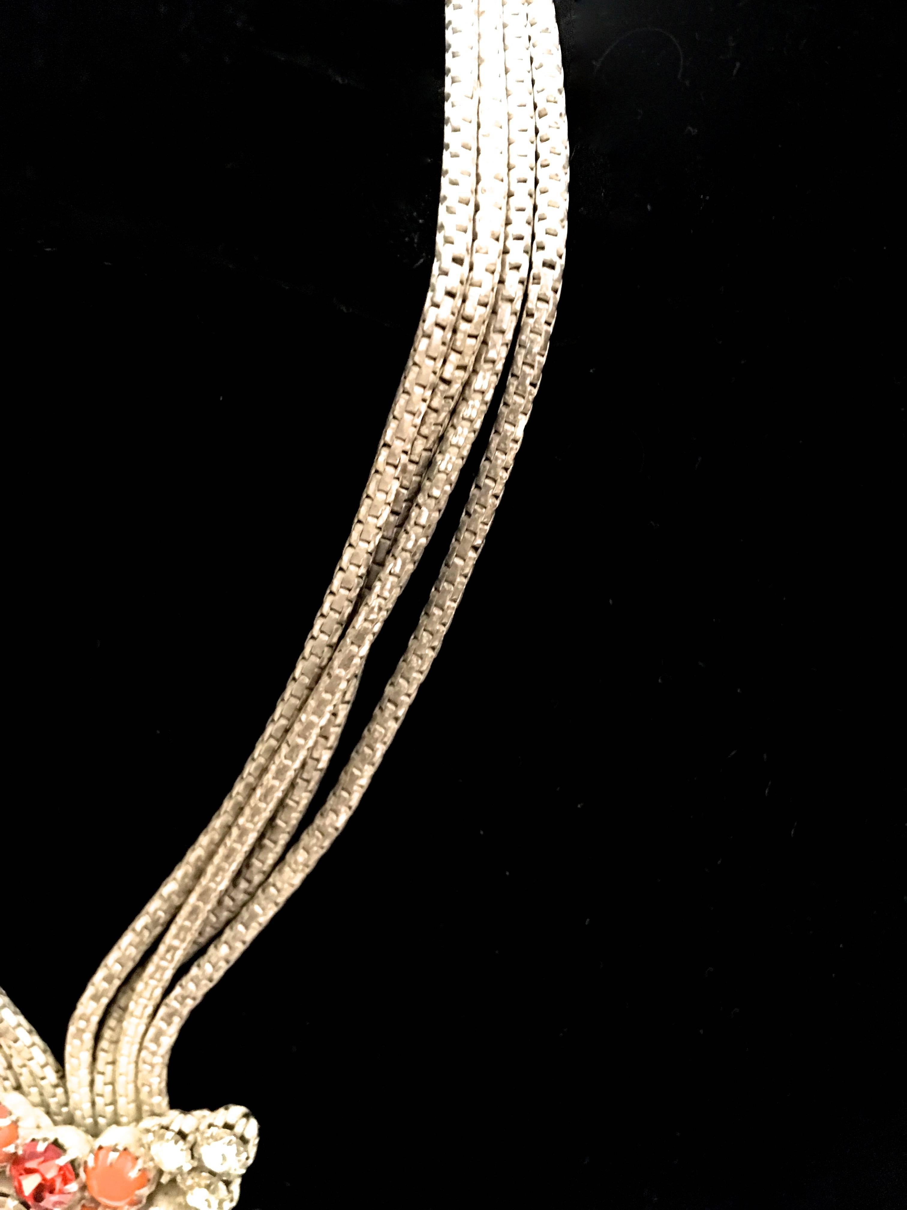 Presented here is a multi-strand rhinestone necklace. The necklace is comprised of four gorgeous bronze tone metal cords that end with a drop at the bottom of the necklace with an mixed array of white, orange and red circular rhinestones.  The metal