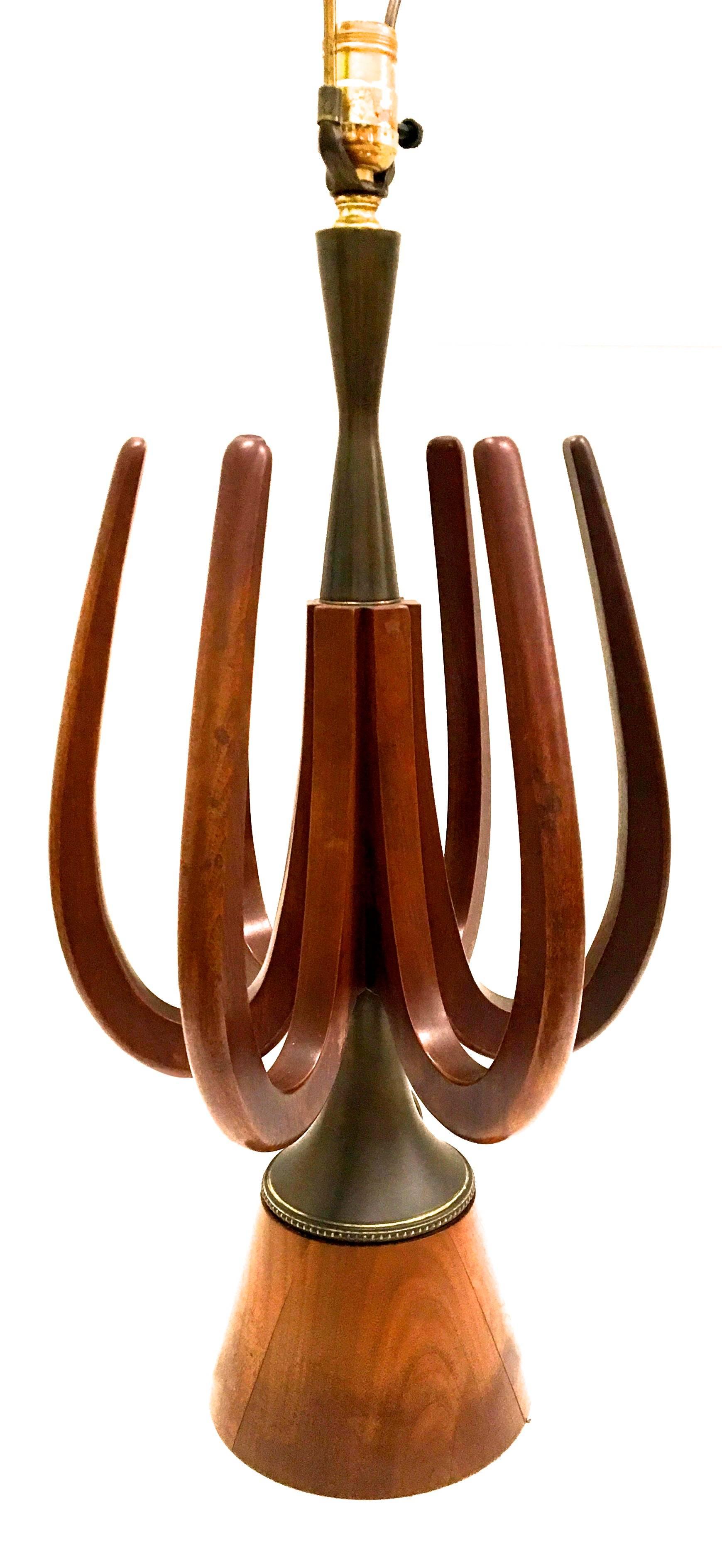 Presented here is a beautiful mid century modern lamp from the late 1960´s early 1970´s. The lamp is hand carved from walnut wood. There are protruding spires the extend out from the base of the lamp and encircle the center of the top. A very unique