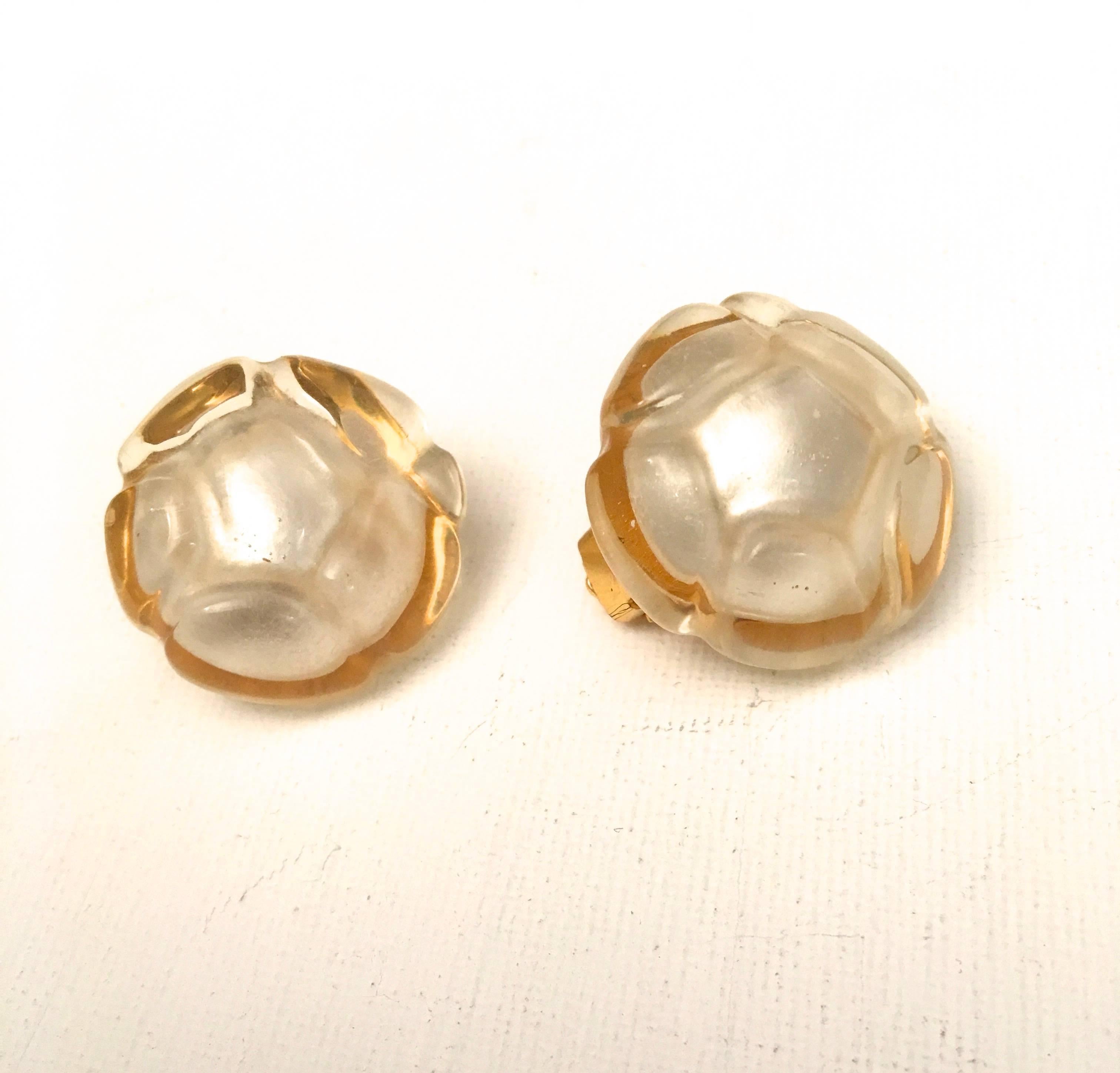 Presented here is a vintage pair of Chanel earrings. These rare earrings are comprised of an opalescent lucite camellia with a backing that is comprised of gold tone metal. They are clip-on earrings. They measure 1.2 inches in diameter. The