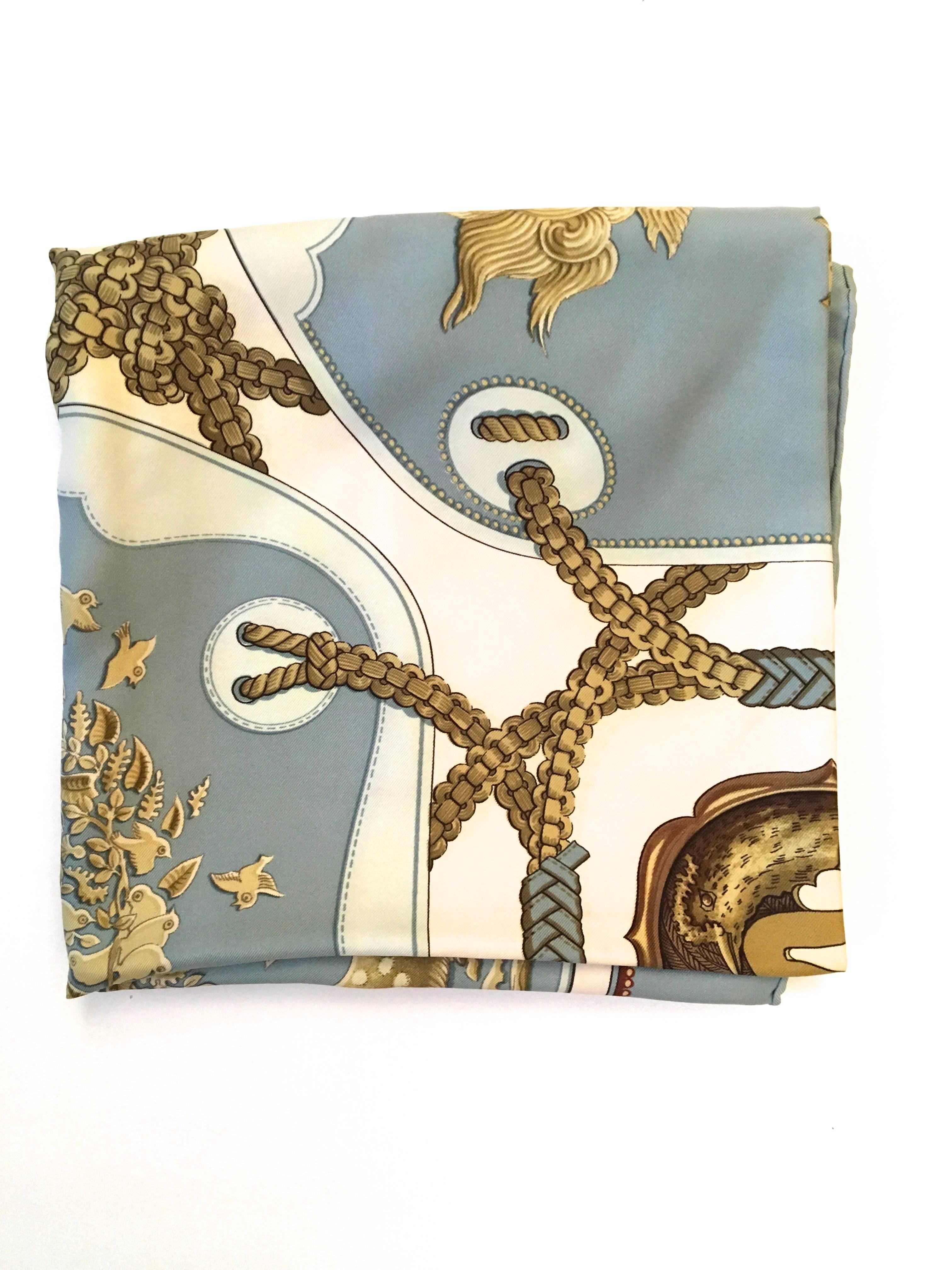 Presented here is a beautiful vintage Hermes scarf. The scarf is 100% silk and is comprised of shades of gray, gold, white, creamy white, browns, blues and blacks. The scarf is a gorgeous print comprised of an interlocking rope and tassel design. In