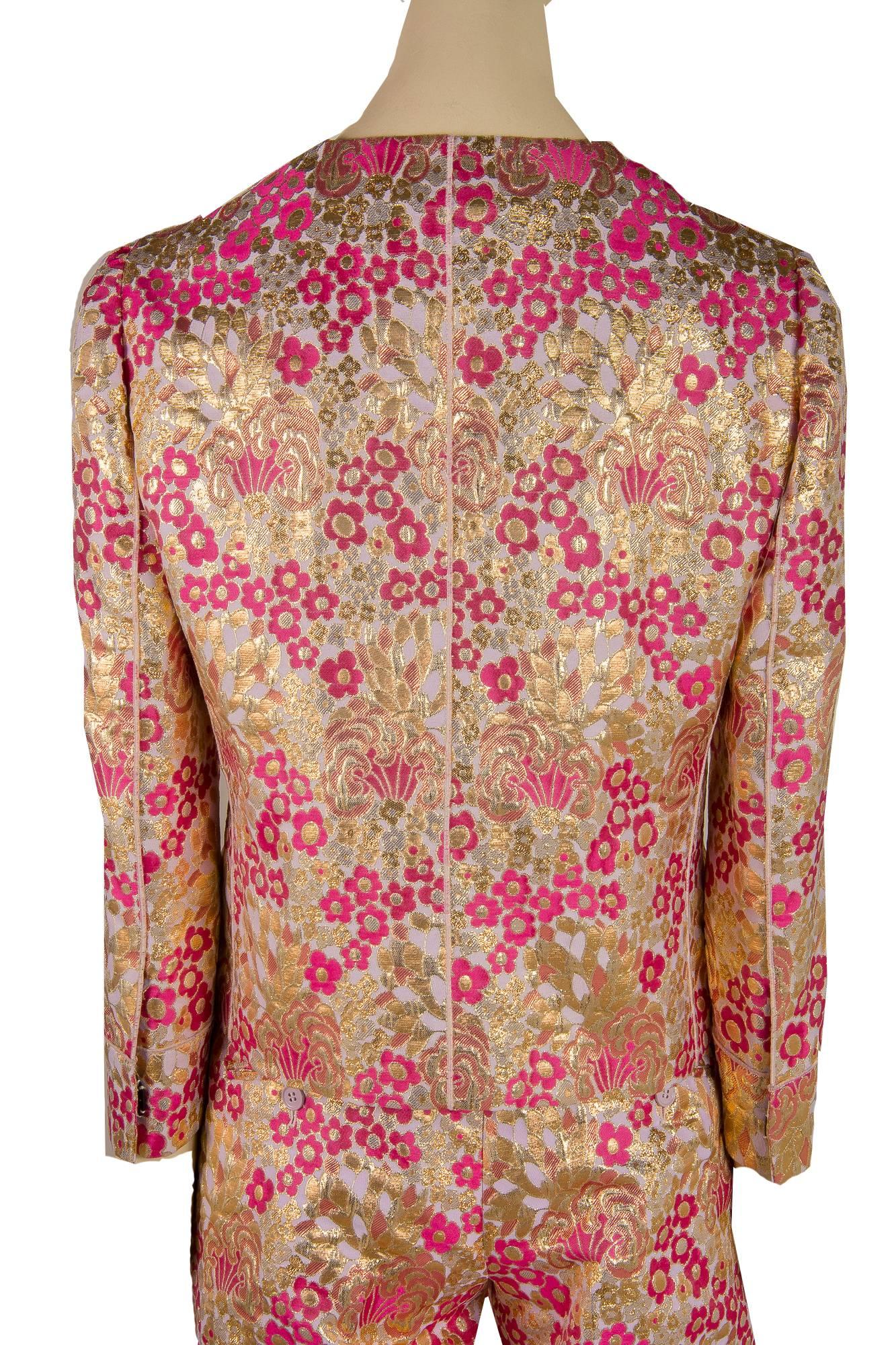 Presented here is a new Dolce and Gabbana button down jacket. The jacket is a size 38. The silk brocade fabric is absolutely magnificent and the fabric is woven threads of gold and light pink and magenta flowers throughout. The measurements for the