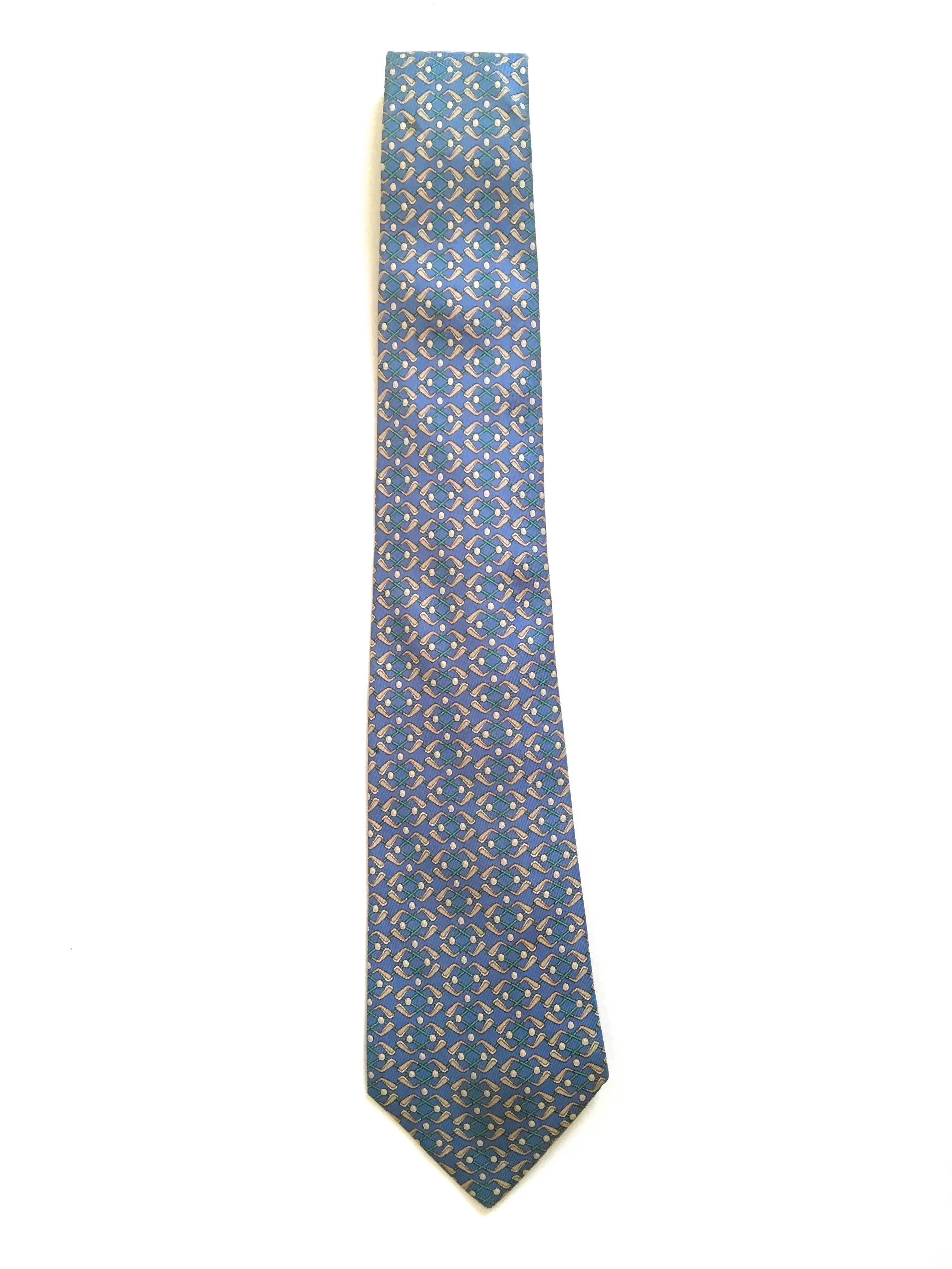 Presented here is a beautiful necktie from Hermes Paris. This beautiful tie has a light blue background. The foreground of the tie is comprised of a tessellation design of golf clubs and golf balls. The necktie measures 60 inches long and 3.5 inches