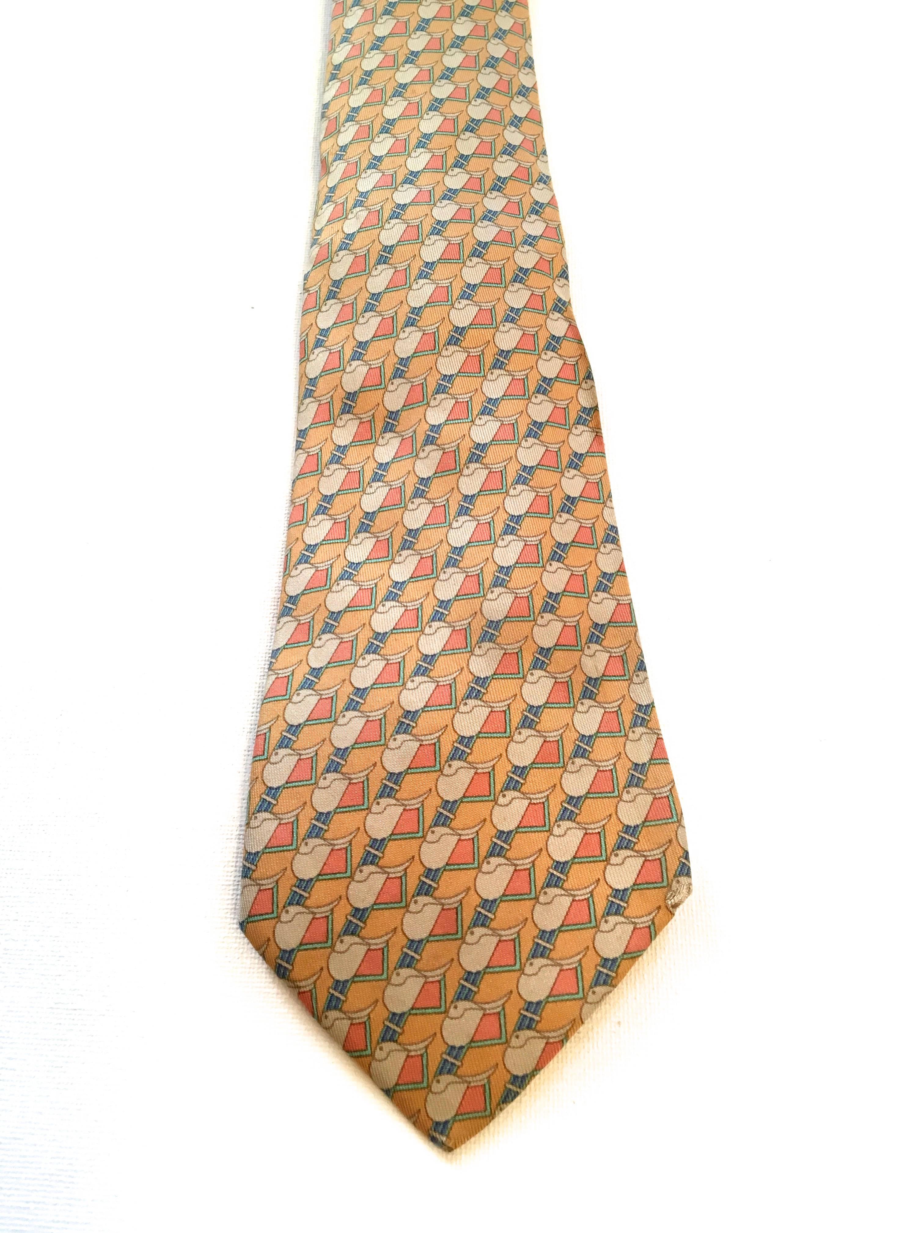 Presented here is a beautiful necktie from Hermes Paris. This beautiful neck tie is a geometric pattern consisting of abstract shapes in a tessellation design. The color is comprised of shades of white, yellow, pink and blue. The tie measures 57