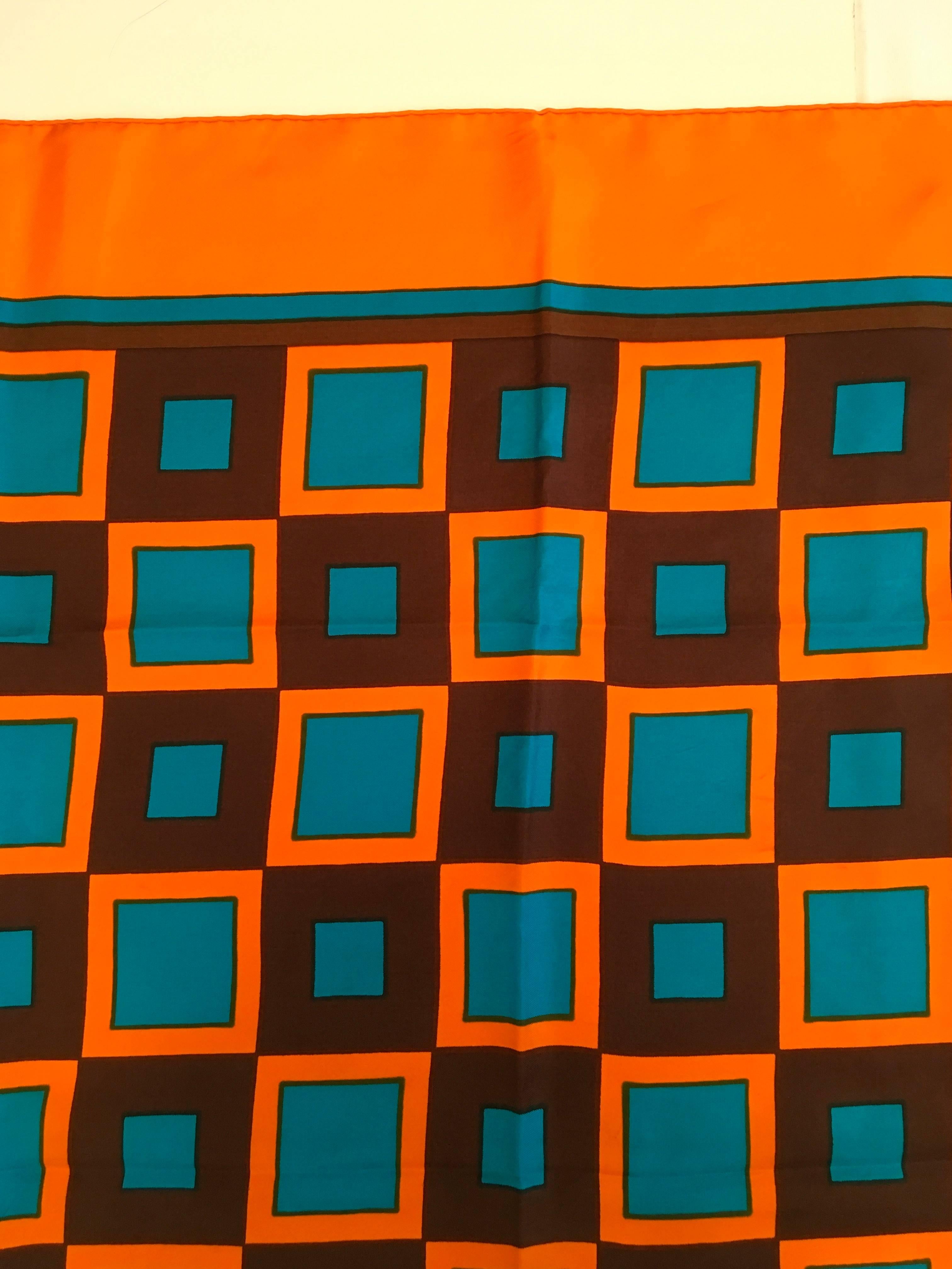Presented here is a beautiful scarf from Yves Saint Laurent (YSL.) This hand rolled scarf is made from 100% silk. The scarf is from the 1980's. The design of the scarf is a composition of orange, brown and blue squares in a gridded almost