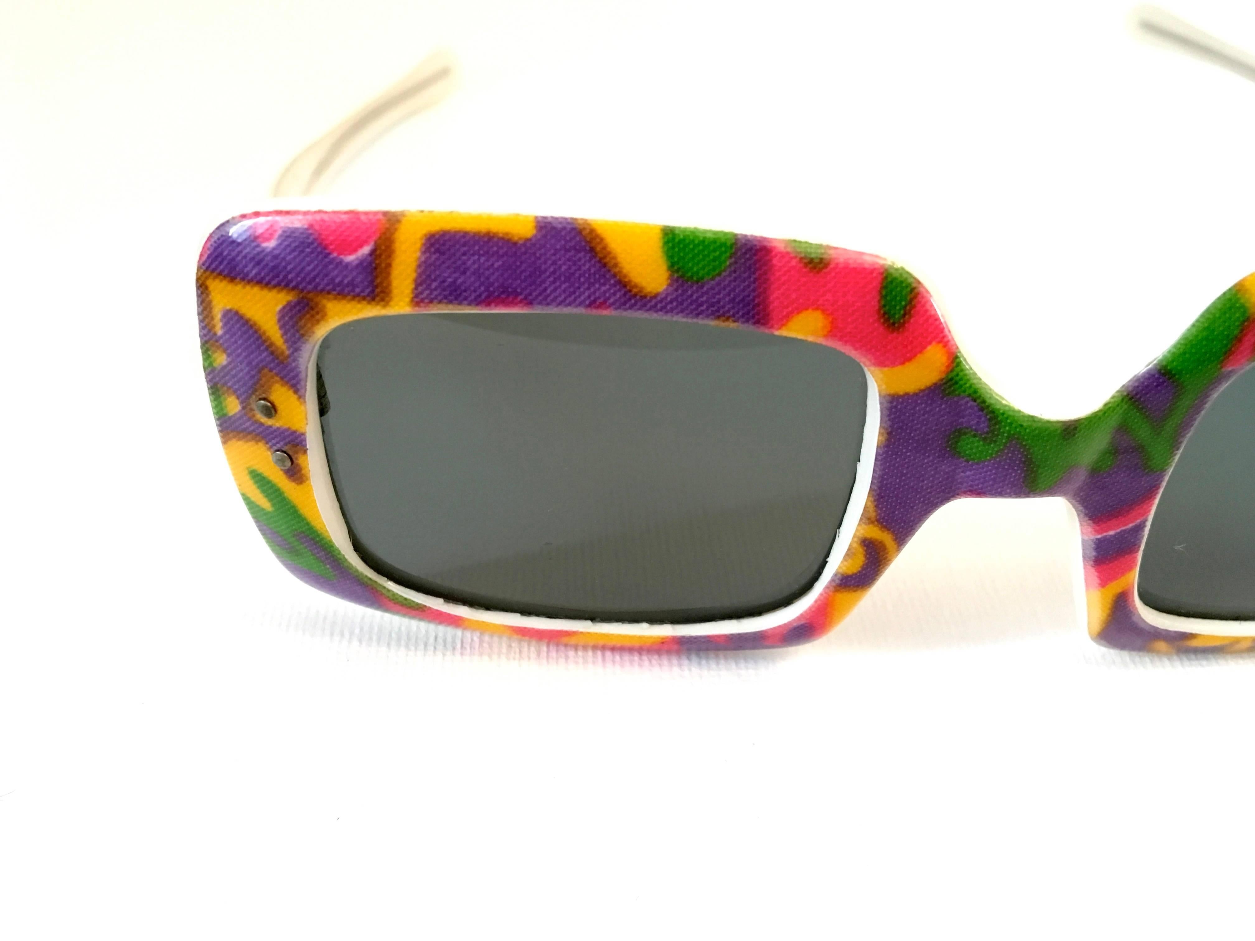 Presented here is a fantastic pair of sunglasses from the 1960's. This mod pair of sunglasses is comprised of a psychadelic colored design on the front of the glasses with a square-like shape of lenses on the front. The back is a combination of