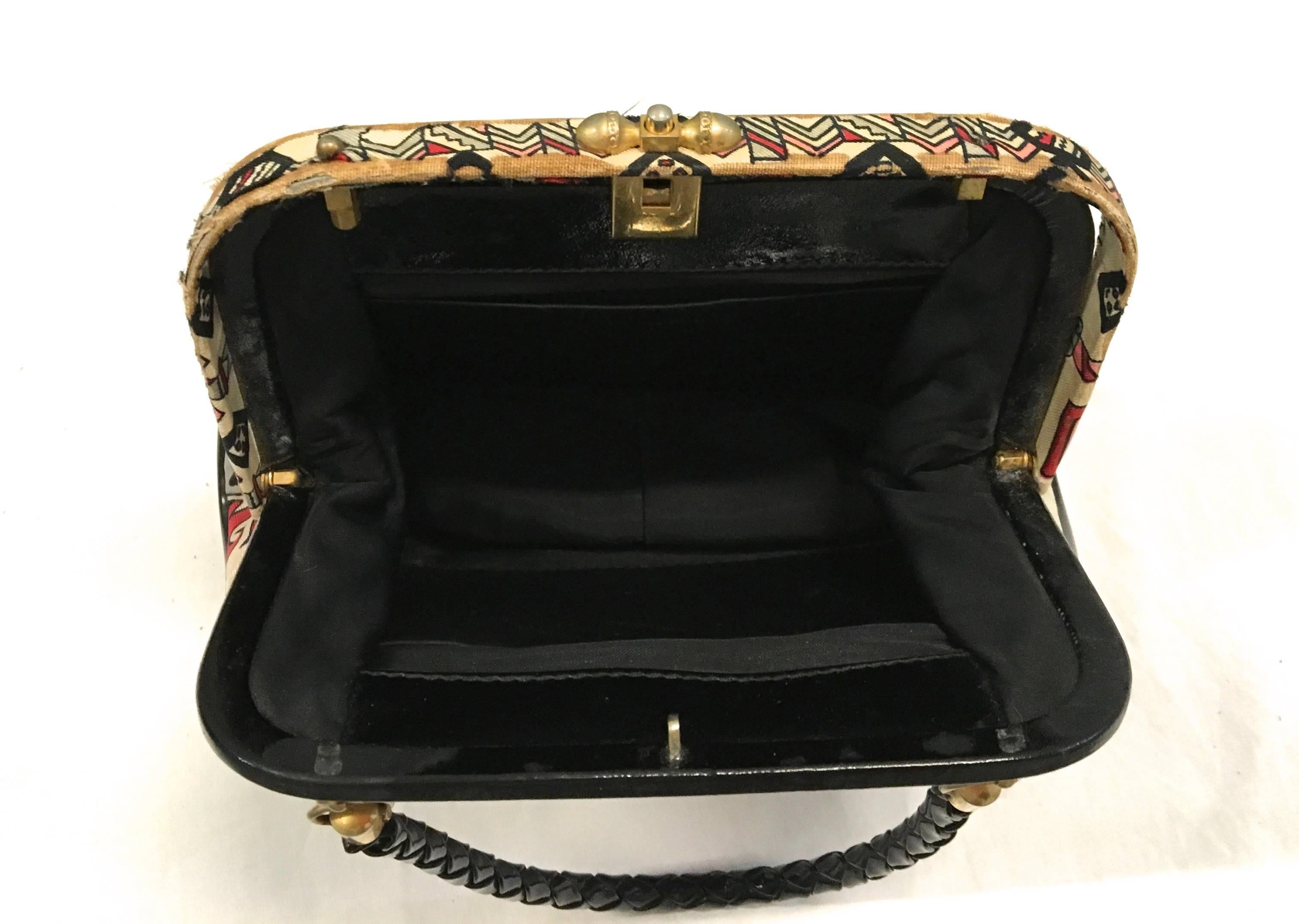 Presented here is a purse from Emilio Pucci. This vintage purse is from the 1960's and is comprised of colors of tones of gray, black, red, cream and white. The bag is trimmed in black with a black handle and gold tone metal hardware. The bag is in
