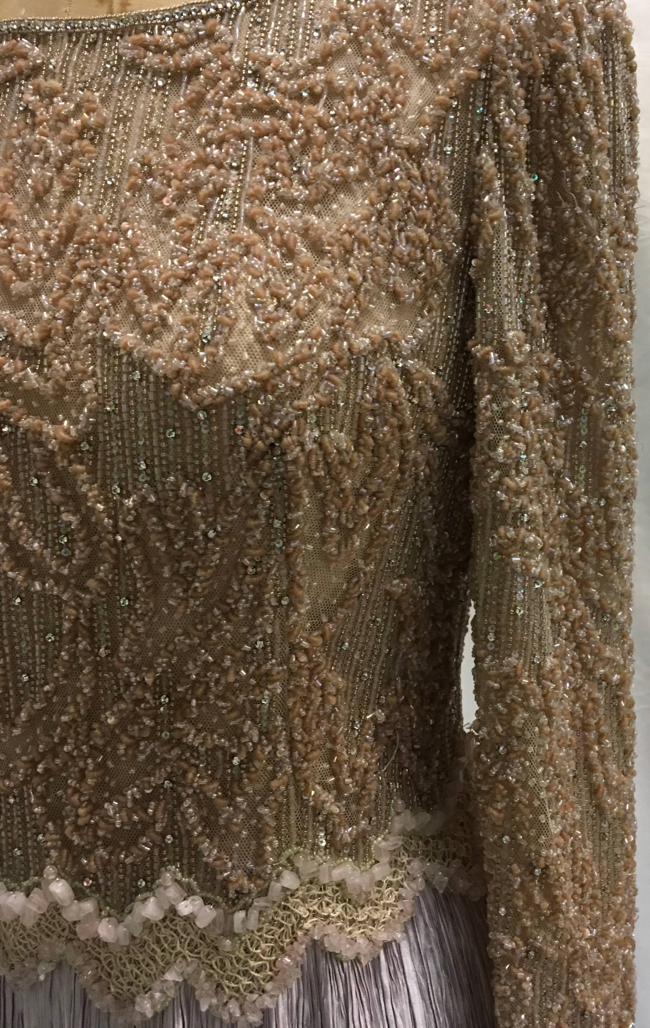 Presented here is a Mary McFadden silk gown couture silk gown with beading and sequins. This stunning 1980's Mary McFadden tan and lavender evening gown is a heavenly masterpiece that takes you back to another time. The fabulous bead and sequin work