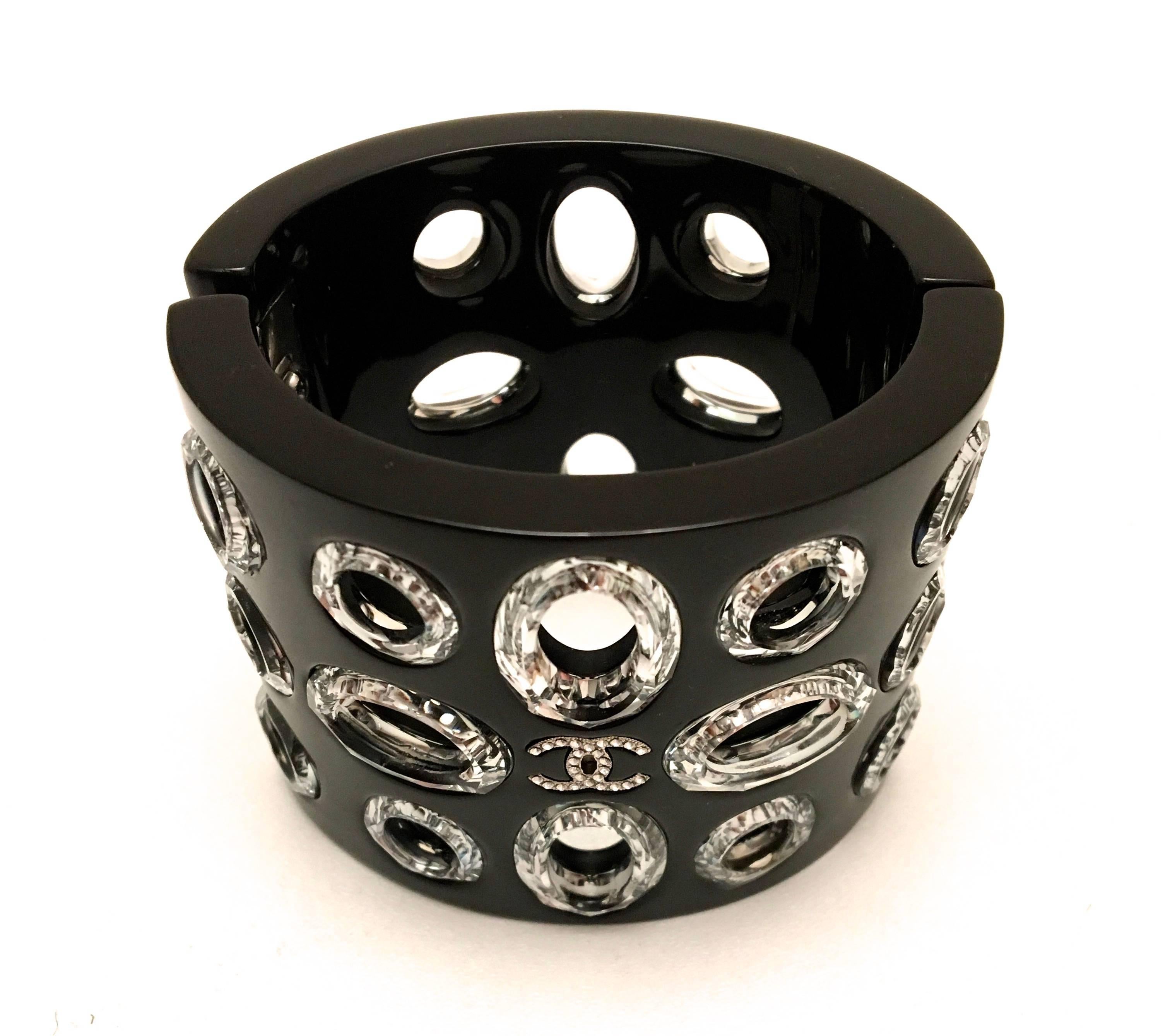 Presented here is a beautiful cuff bracelet from Chanel. This extra long cuff bracelet is comprised of a black lucite frame with small circles with encased crystals. There is also a highlighted series of rhinestones forming a CC logo. The bracelet
