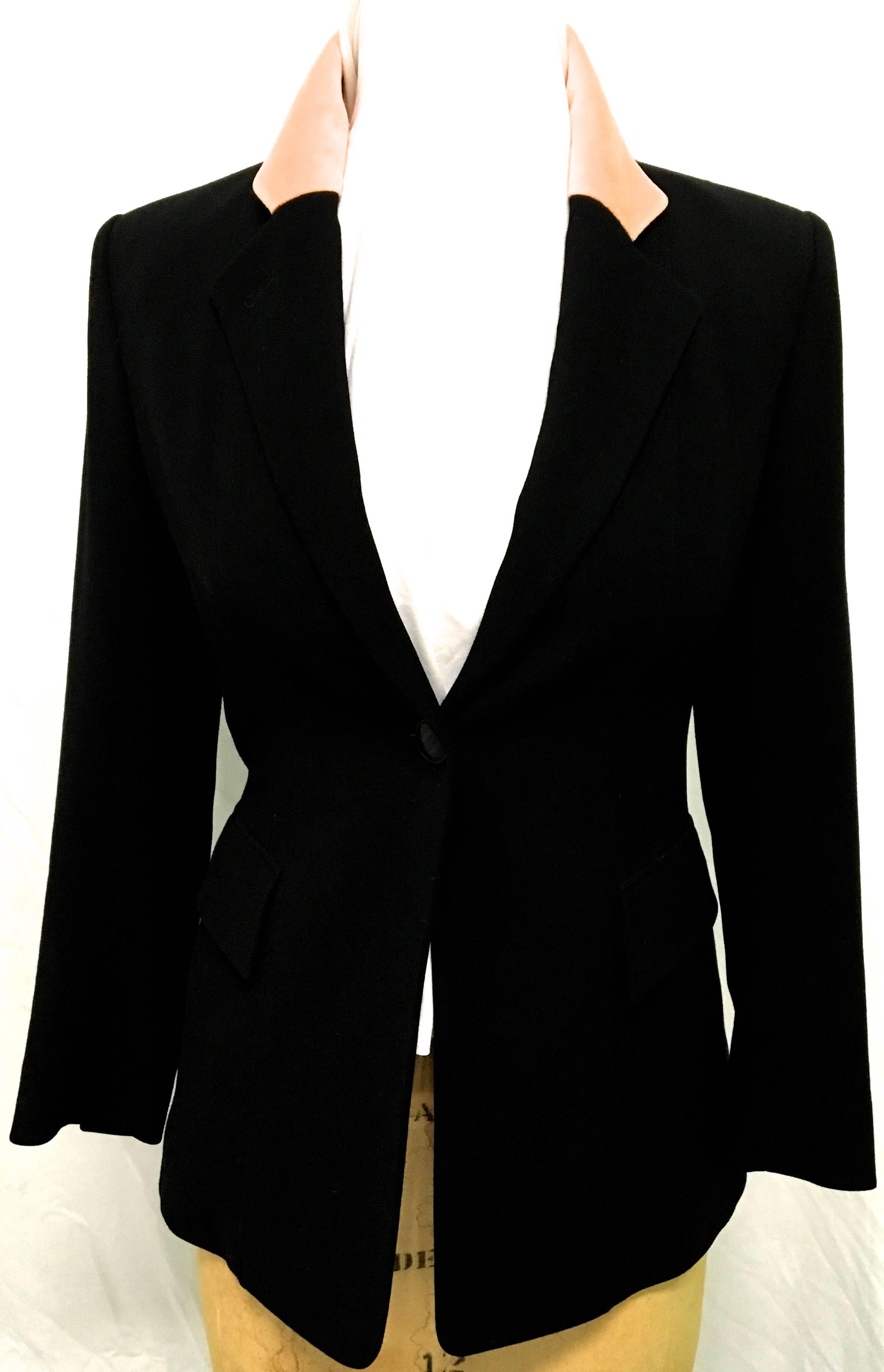 Presented here is a gorgeous women's blazer by Hermes Paris from the 1980's. This fabulous blazer is comprised of black soft wool on the exterior and is lined in acetate along the interior. There is a beautiful peach colored collar that adds a nice