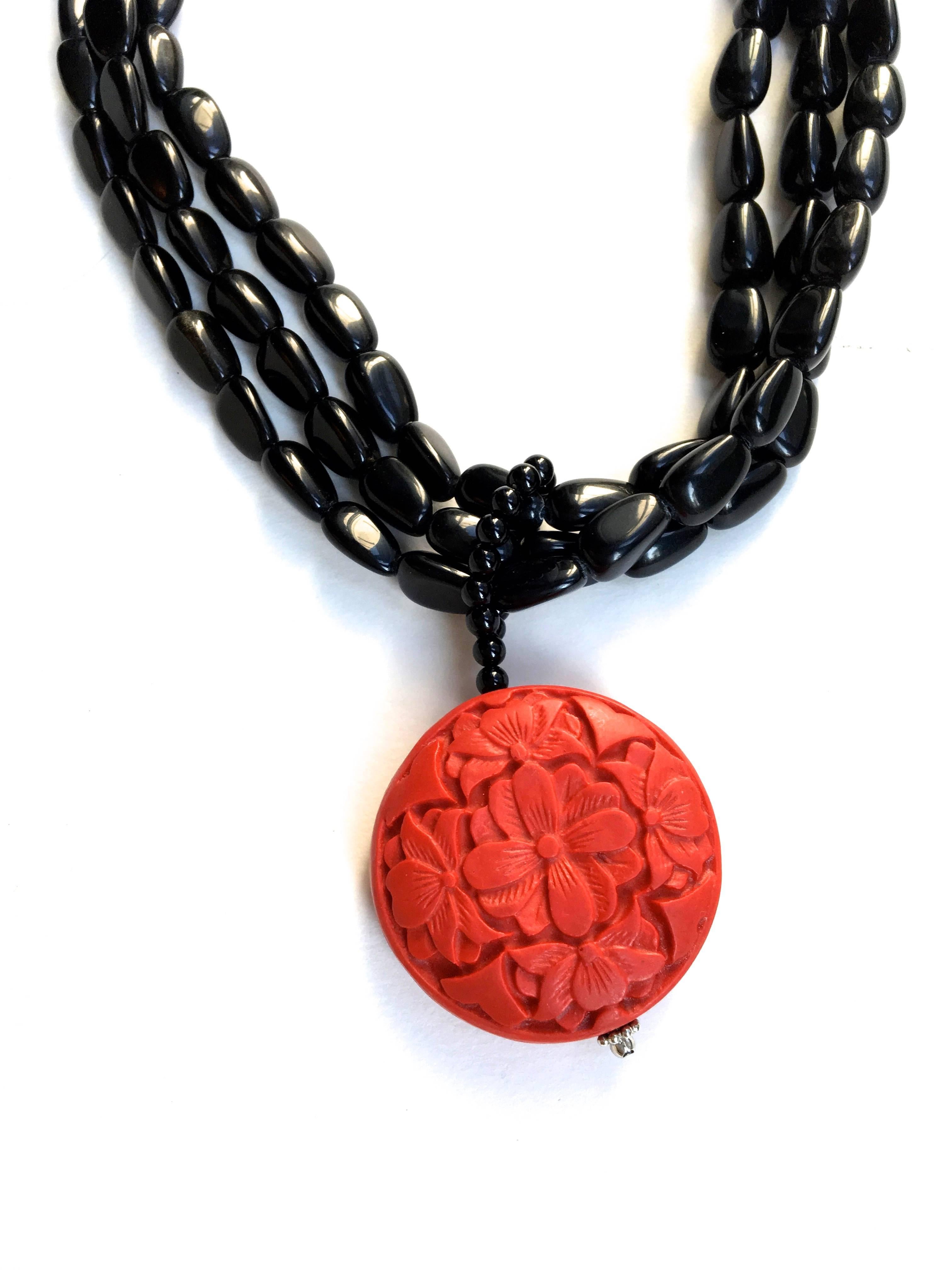 Presented here is a fabulous Asian pendant necklace. This necklace is comprised of three strands of black beads strung together with a hook clasp at the back. The main pendant on the necklace is a gorgeously articulated piece of cinnabar with