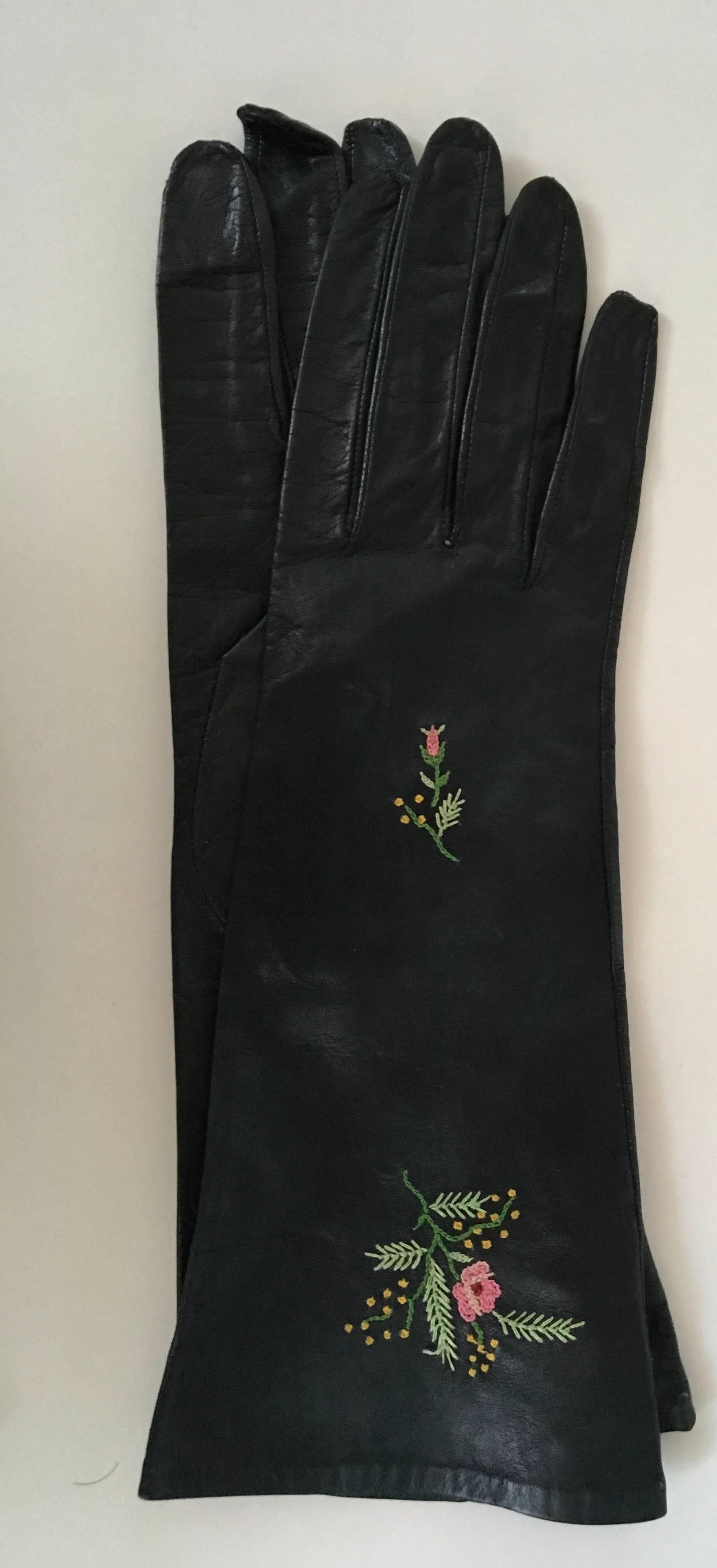 Presented here are two never used new gloves from the late 50's. One pair is comprised of beautiful black leather with hand stitched floral design in a size 6. The beautiful gloves seem small because ladies hands in the 60's were smaller. They