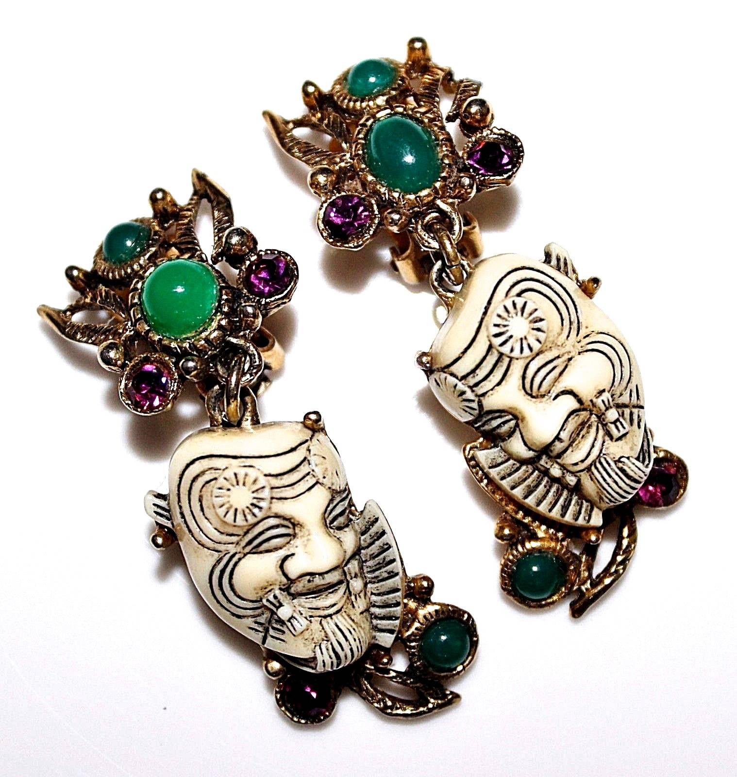 Presesnted here is an extremely rare pair of earrings from Selro. This signed pair of earrings features an Asian devil 'Noh.' This pair of dangle earrings is comprised of a gold tone metal frame with encrusted cabochon gems. The pair of earrings