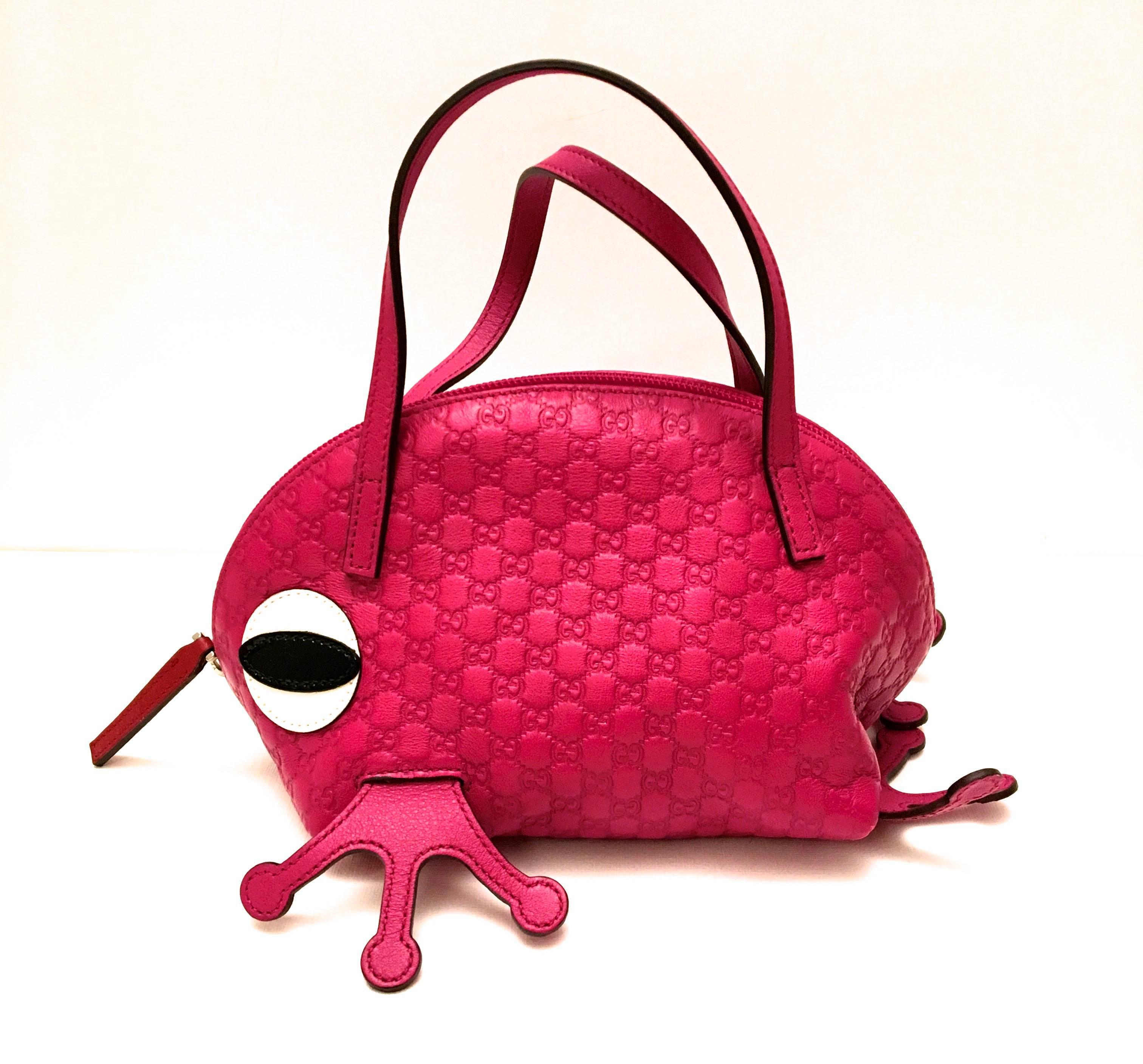 Presented here is an extremely rare and highly collectible limited edition Gucci leather miniature handbag. This adorable little top handle bag is comprised of a rich magenta leather with the signature Gucci logo imprinted across the soft grain