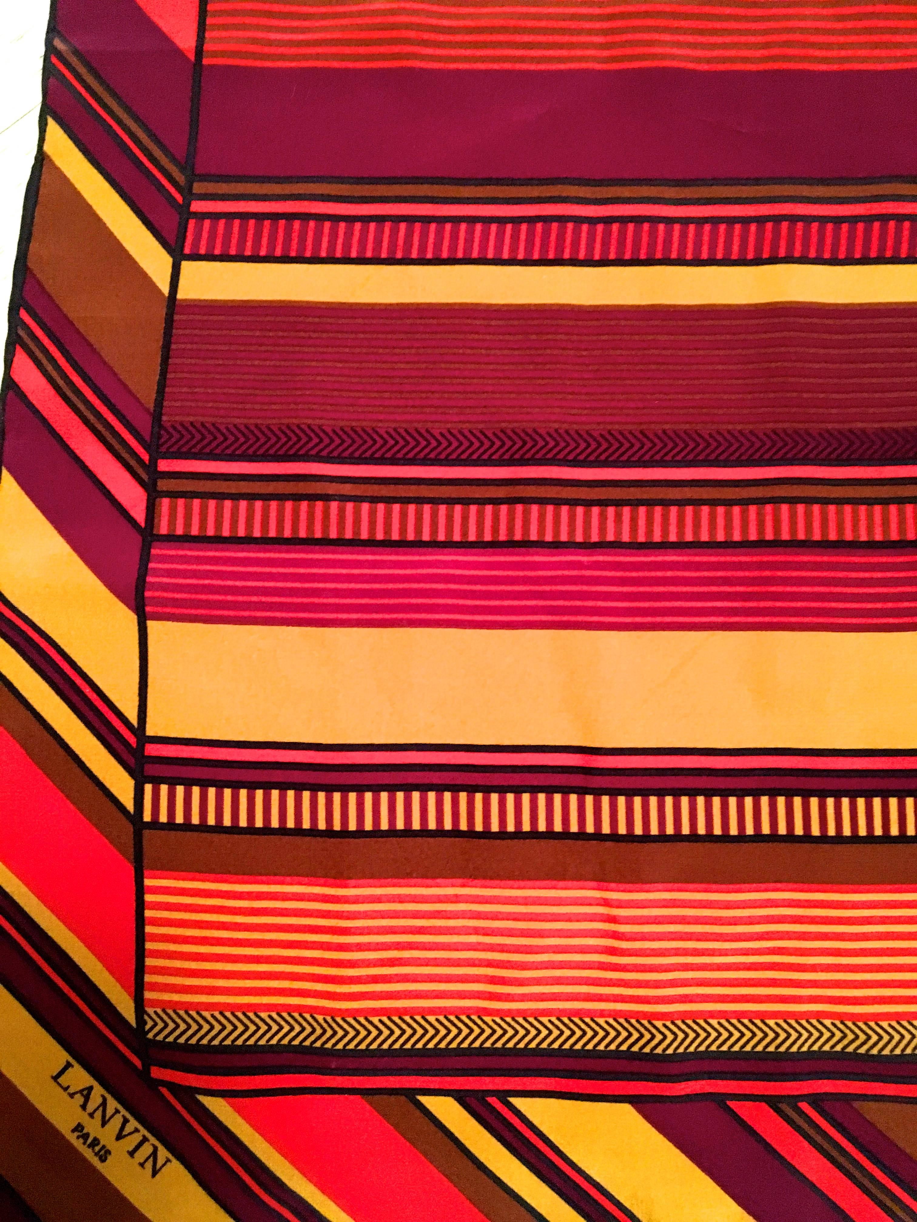 Presented here is a rare vintage scarf from Lanvin. This beautiful vintage scarf is comprised of an autumn colored design of shades of yellow, red, orange, brown and black displayed in horizontal stripes across the majority of the body of the scarf