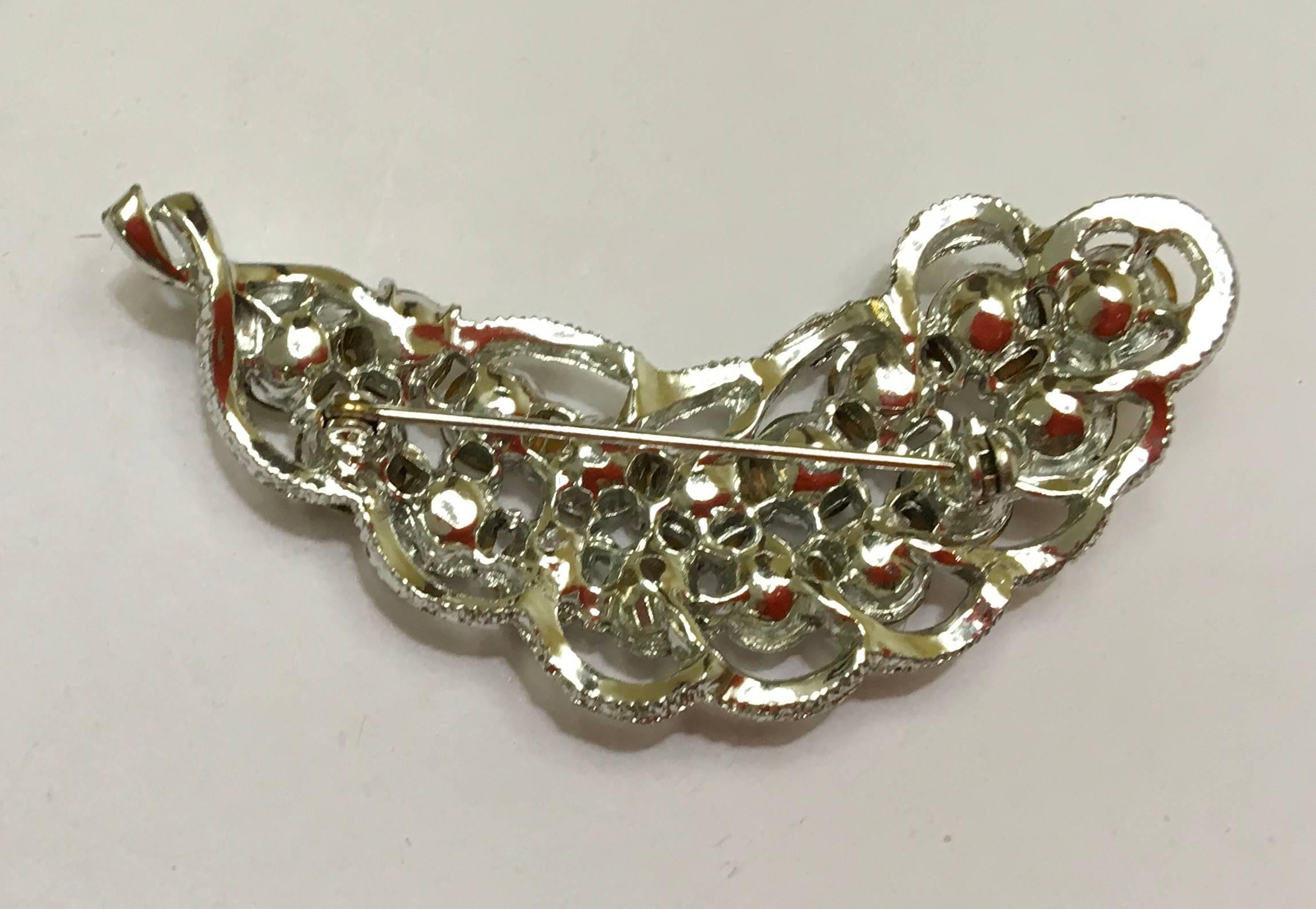 Presented here is a beautiful rhinestone brooch from the 1960's. This brooch is adorned with circular rhinestones and has metal filigree around the exterior of the brooch. There is a pin on the back of the brooch that closes with a clasp. A gorgeous