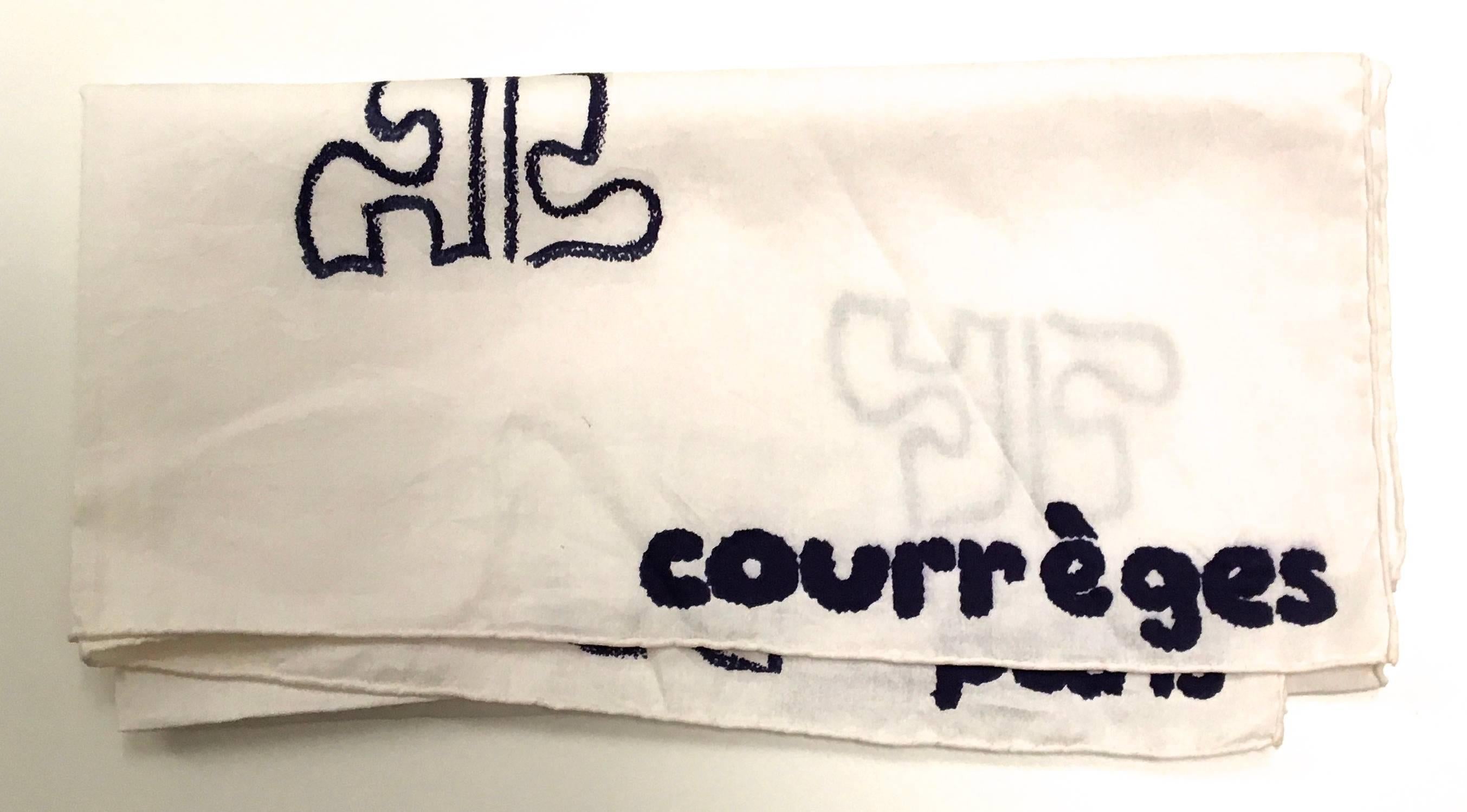 Presented here is a beautiful scarf from Courreges Paris. This rare scarf is made from 100% cotton. The scarf is a solid white background with the Courreges insignia printed throughout the body of the scarf with blue outlining. The scarf is also