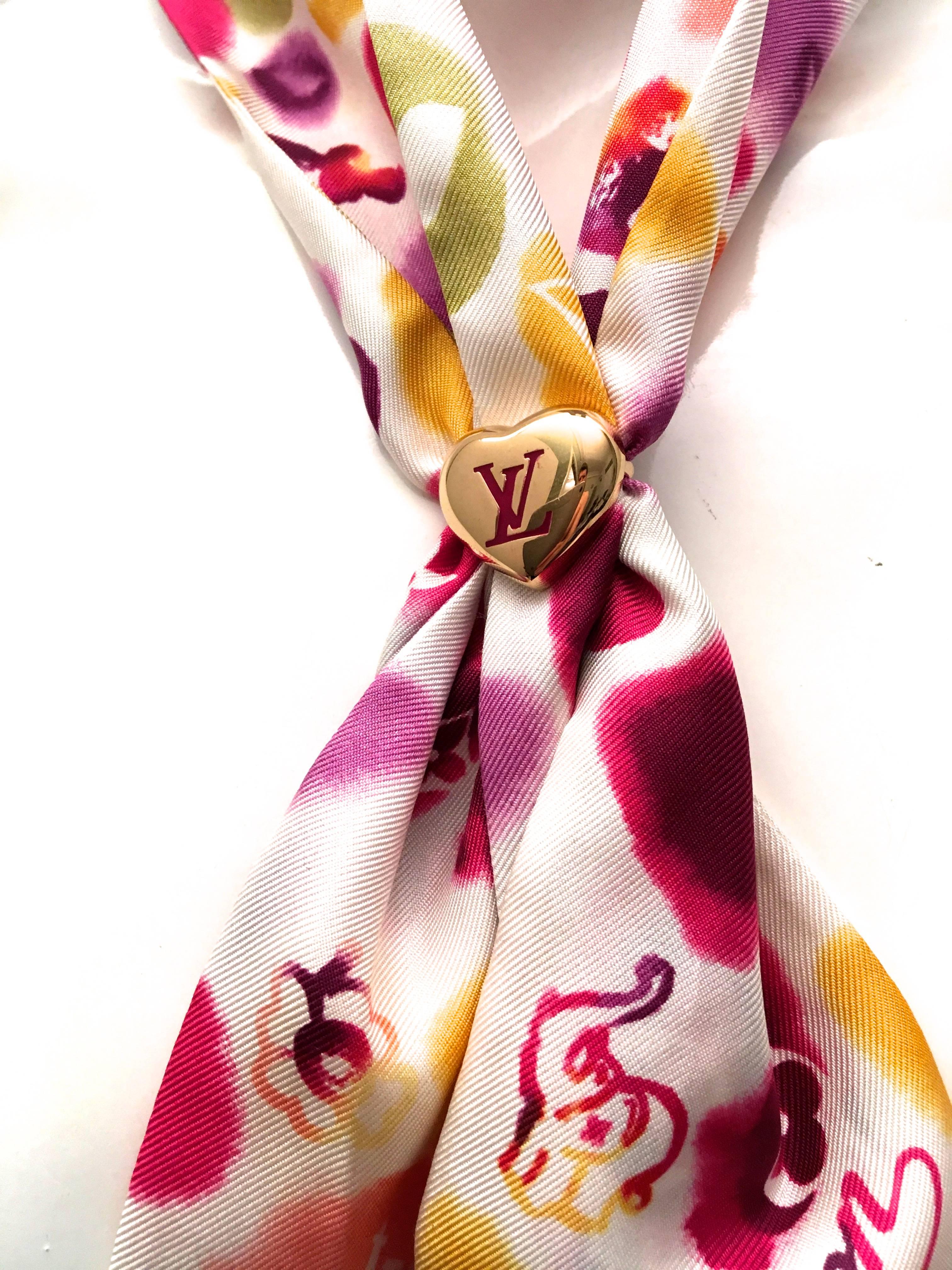 Presented here is a silk scarf from Louis Vuitton Paris. This beautiful scarf is comprised of a series of colorful watercolor style graphics against a creamy white background. The colors of the images are varying shades yellow, green, purple, pink