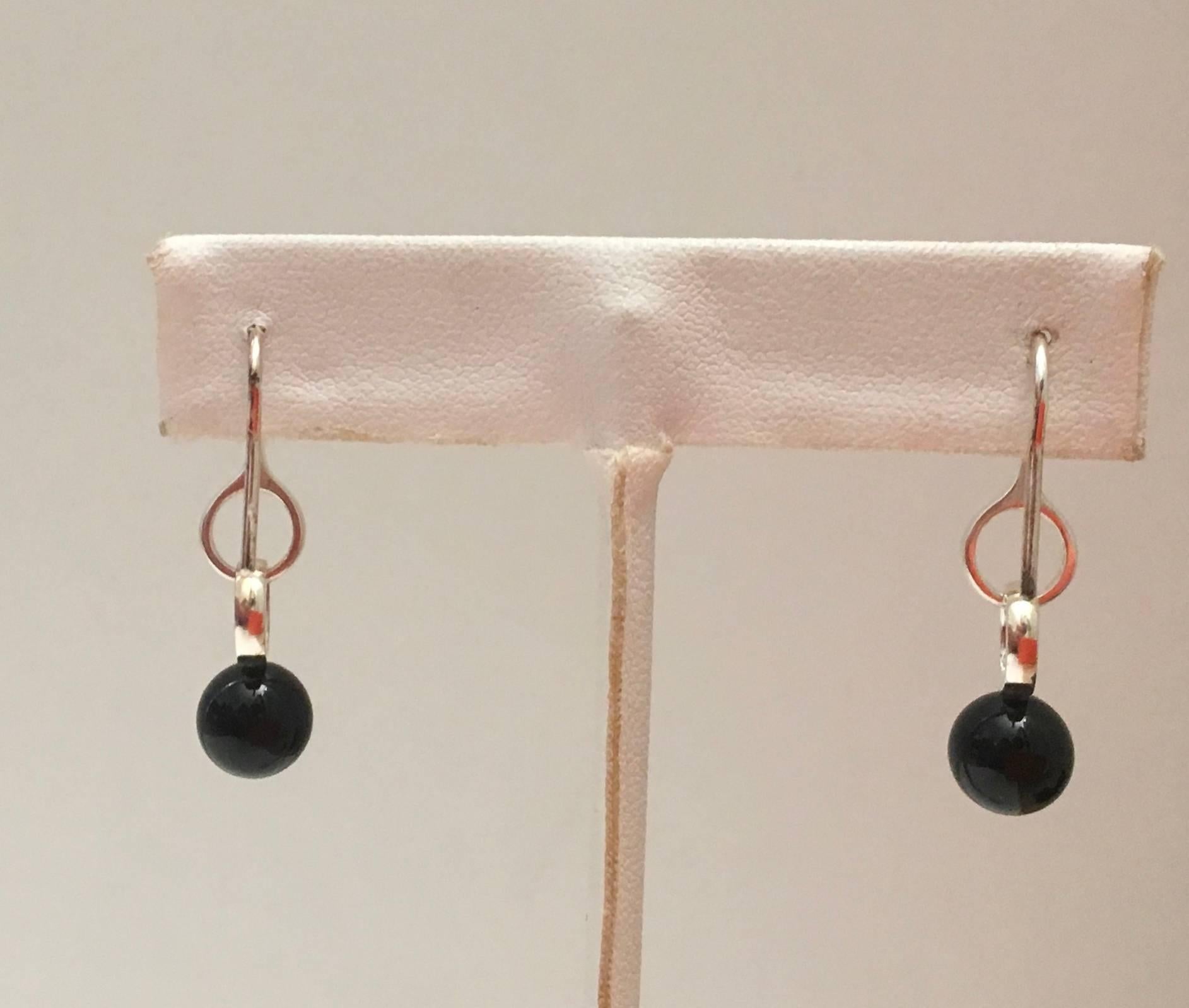Presented here is a new beautiful pair of earrings from Georg Jensen. This lovely pair of earrings is designed for pierced ears and has a black onyx stone suspended from two rings of silver. The earrings are signed by Georg Jensen with an engraving.