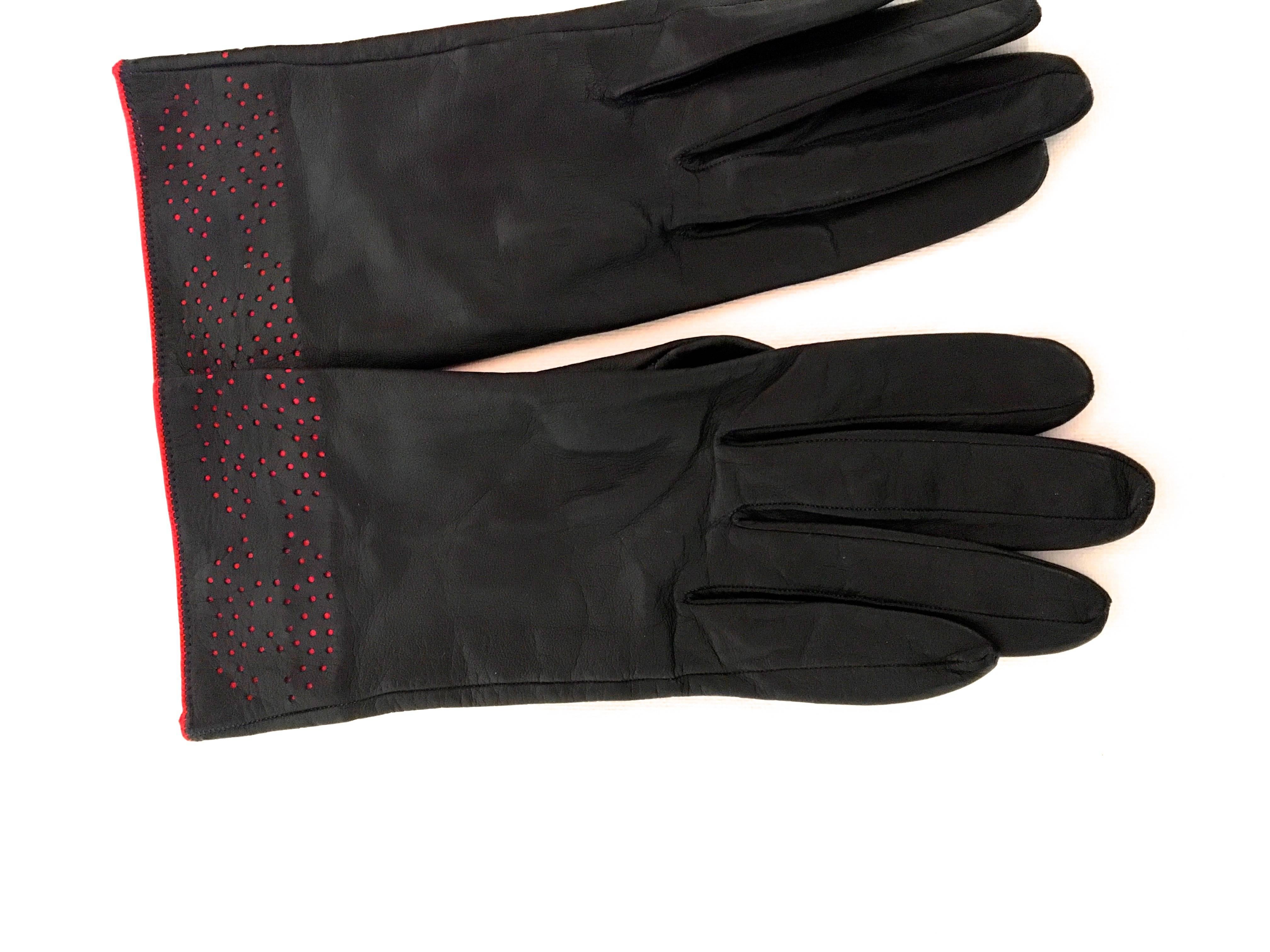 Presented here is a beautiful pair of Chanel leather gloves. This fantastic pair of Chanel gloves is comprised of a rich navy blue leather with red trim along the seams. The Chanel CC logo is perforated into the gloves. The total length of this pair