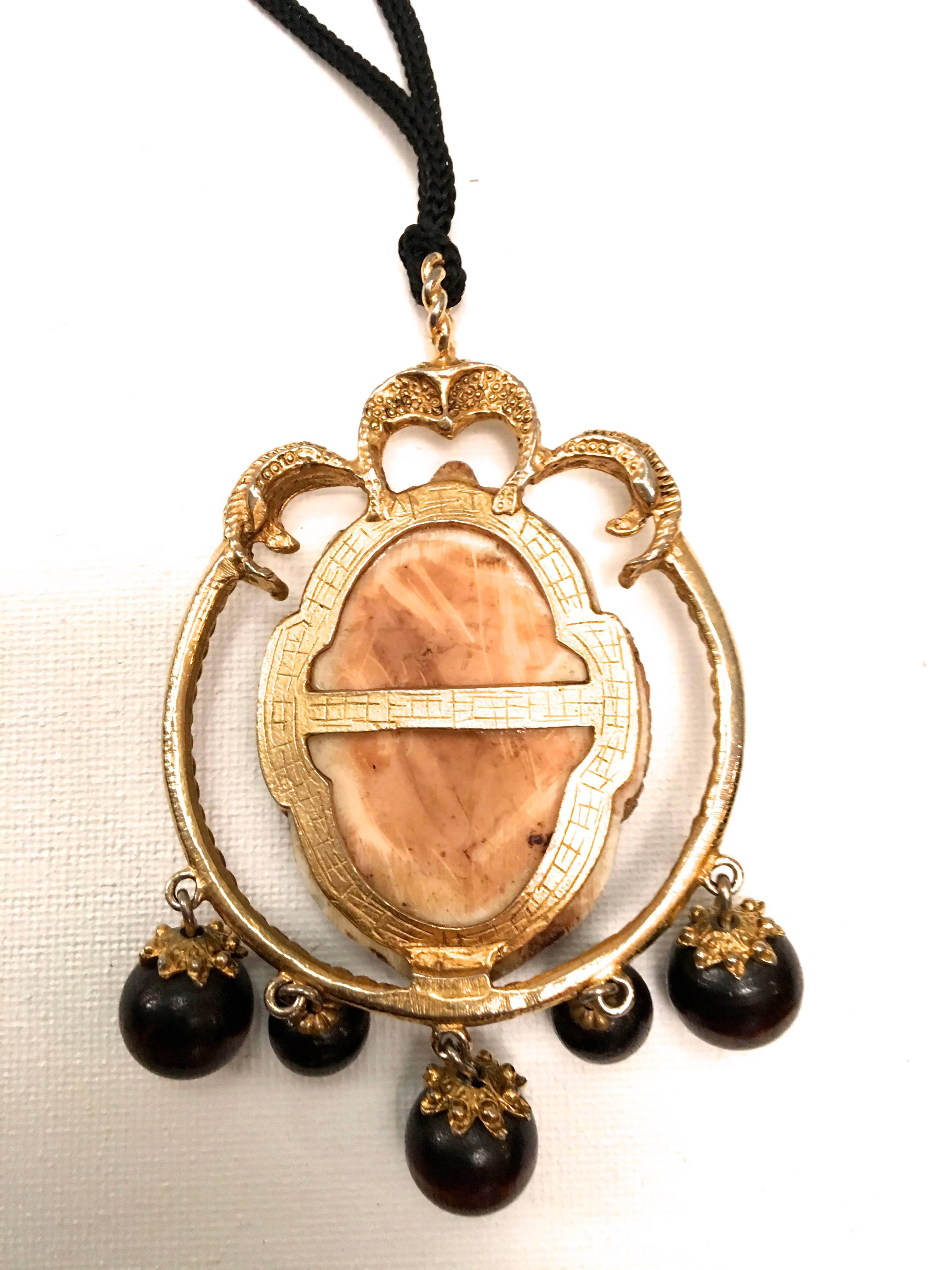 Presented here is a rare necklace from Selro. The necklace is comprised of a pendant of an Asian warrior with a beard. The pendant of the Asian warrior is encased by a gold tone metal frame. There are small decorative beads that dangle from the