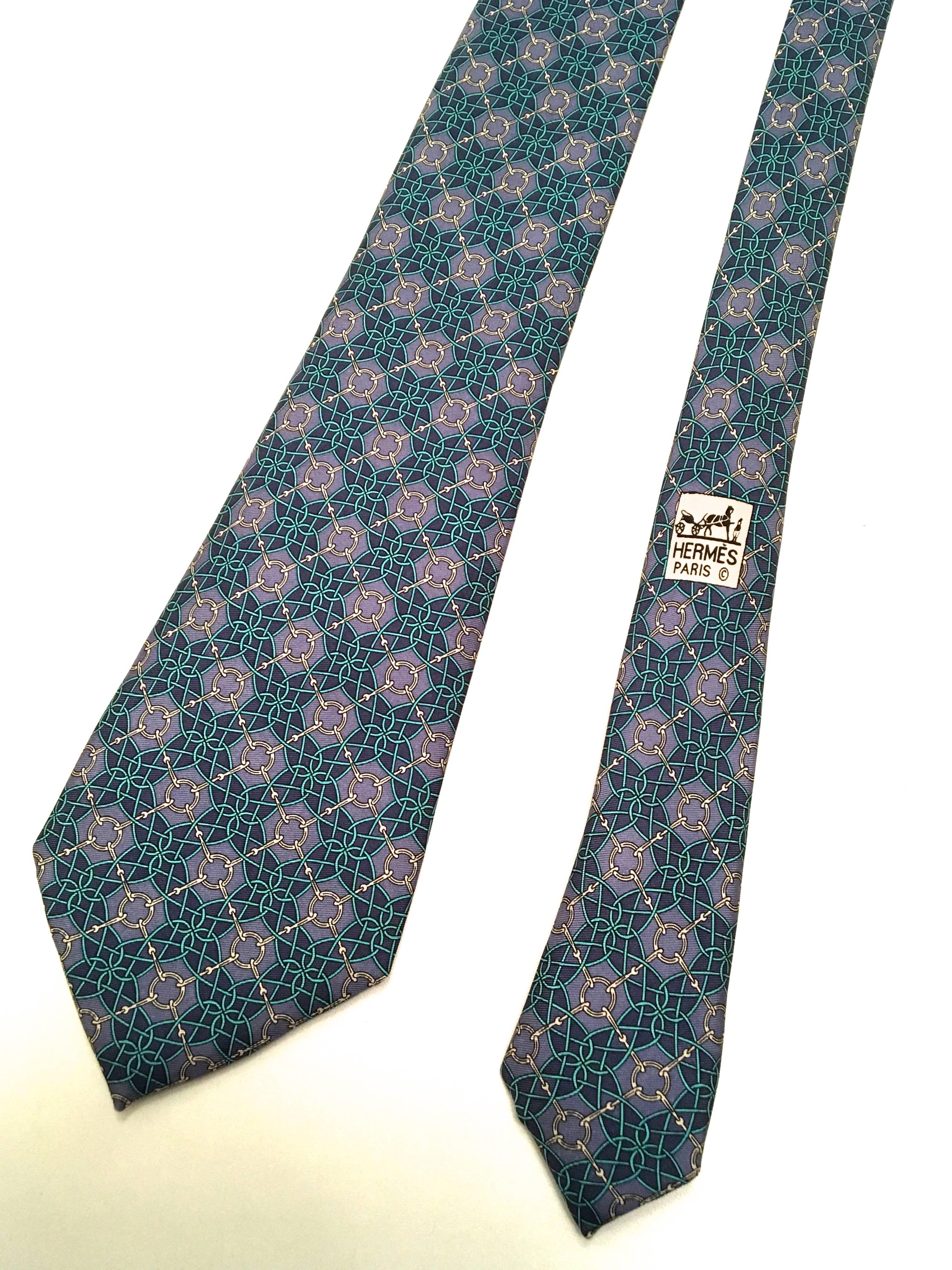 Presented here is a beautiful necktie from Hermes Paris. This beautiful  tie is a geometric pattern consisting of abstract shapes in a tessellation design. The color is comprised of shades of blue, purple and green. The tie measures  3.5 inches wide