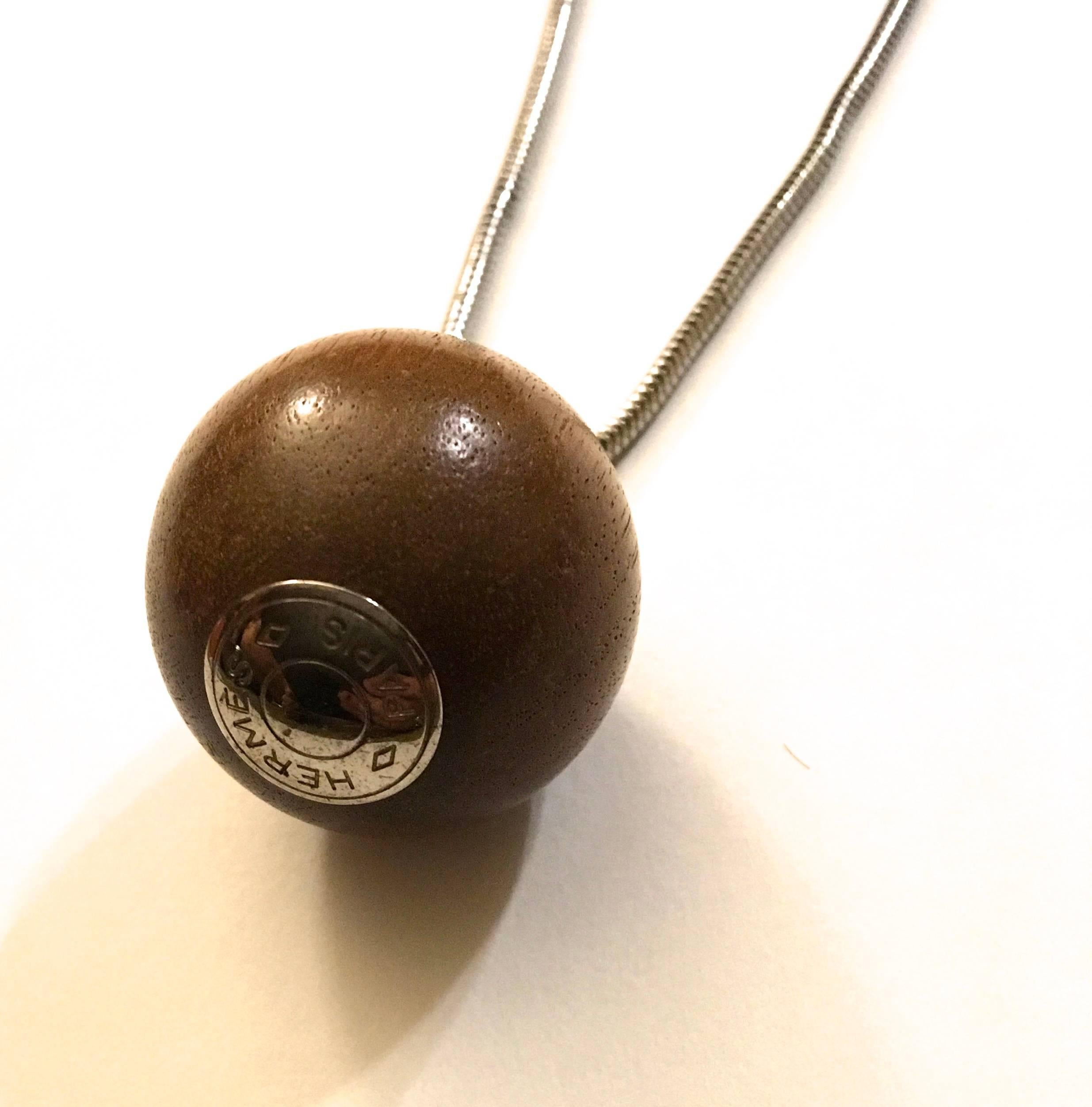 Presented here is a beautiful Hermes necklace with a 24 inch chain and 1 inch round wood ball with silver at the bottom which read HERMES PARIS.