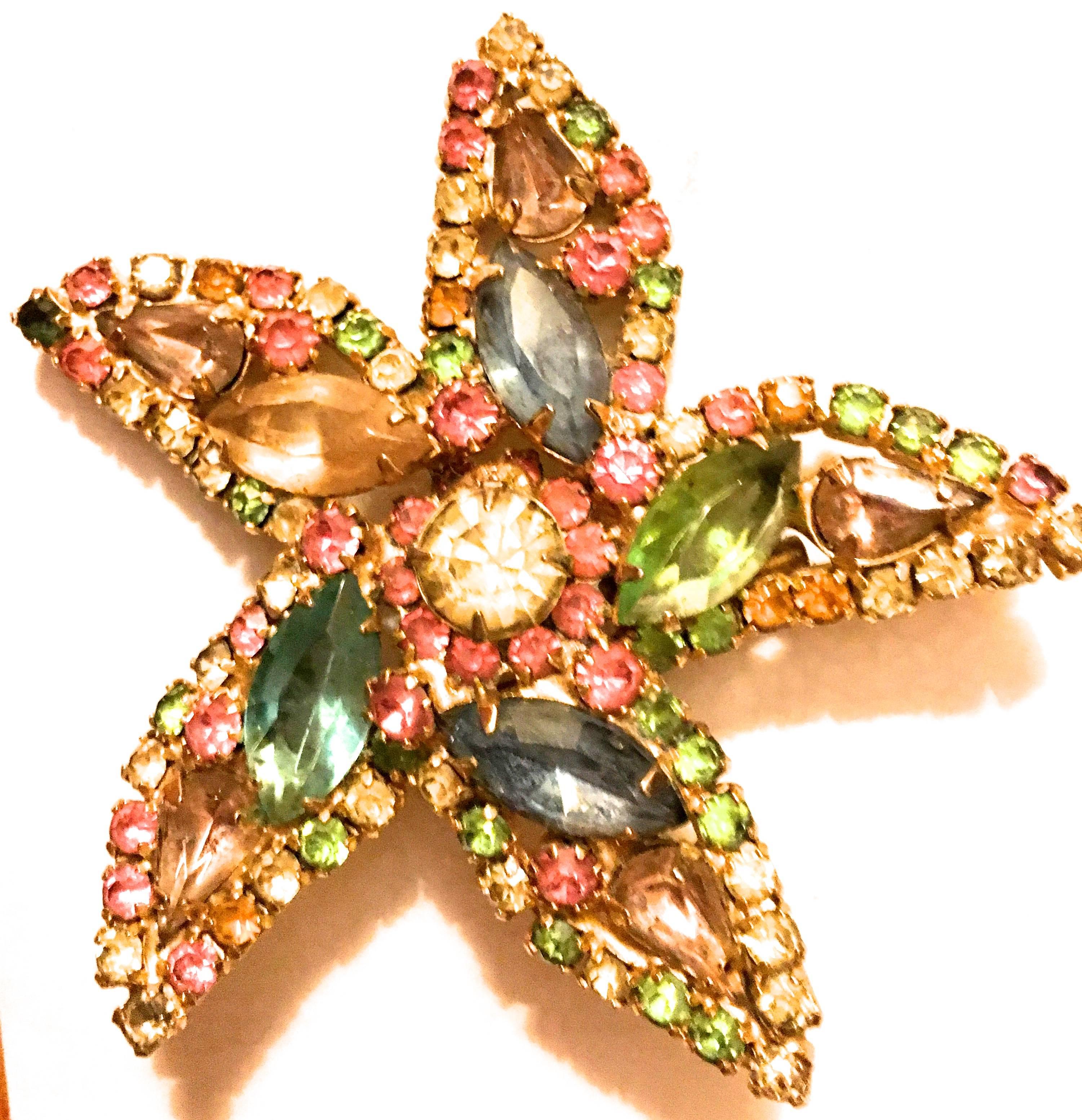 Presented here is a beautiful brooch by Kenneth Jay Lane (KJL) from the 1960's. This lovely vintage brooch is comprised of a gold tone metal base with varying colors of faceted rhinestones throughout. The reverse of the pin is signed by Kenneth Jay