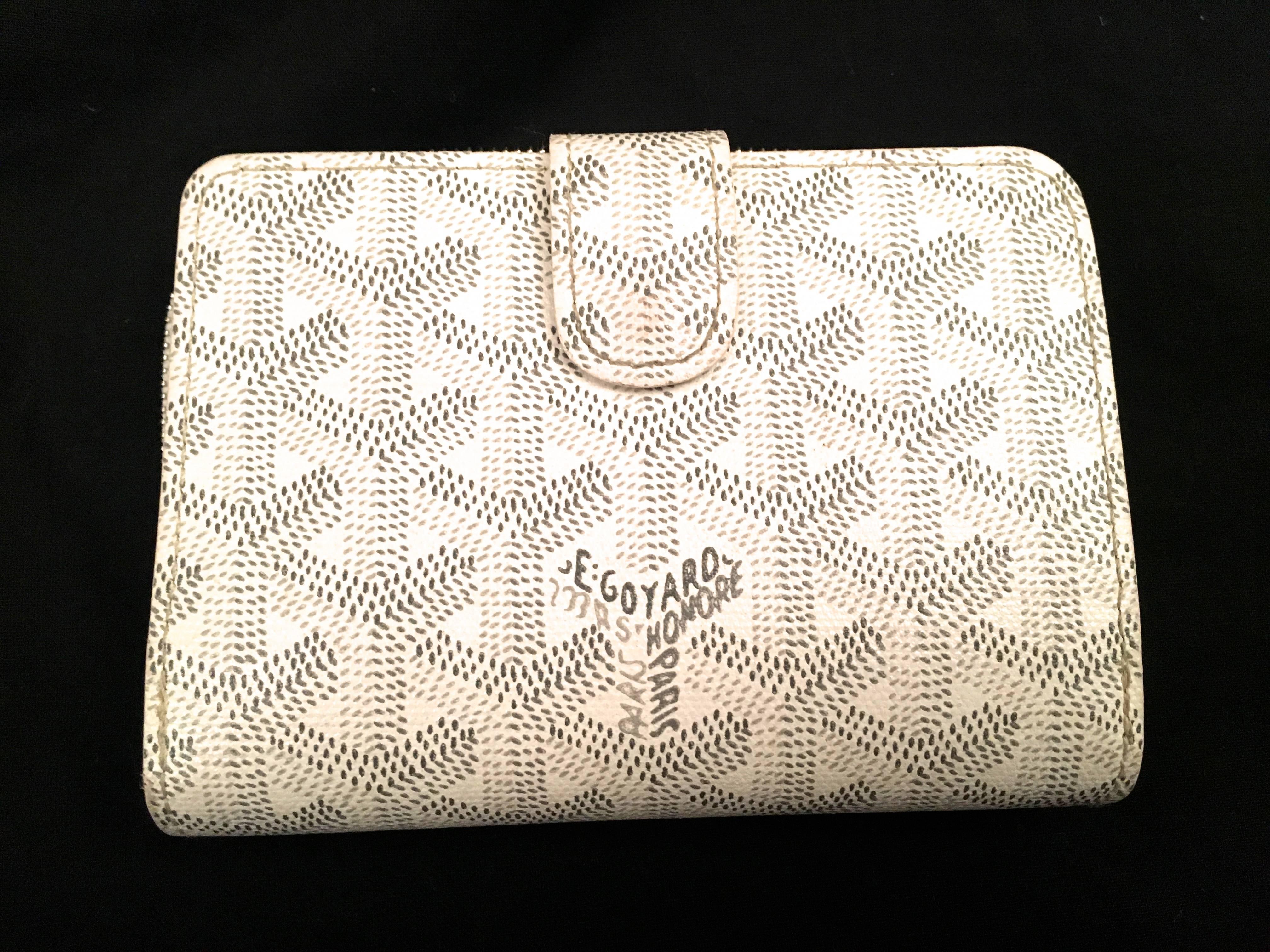 Presented here is a beautiful wallet from Goyard. This wallet has the iconic Goyard tessellation print on the outside of the wallet in white. There are two ways to open the wallet. One is with the button snap. When the button snap is opened, a