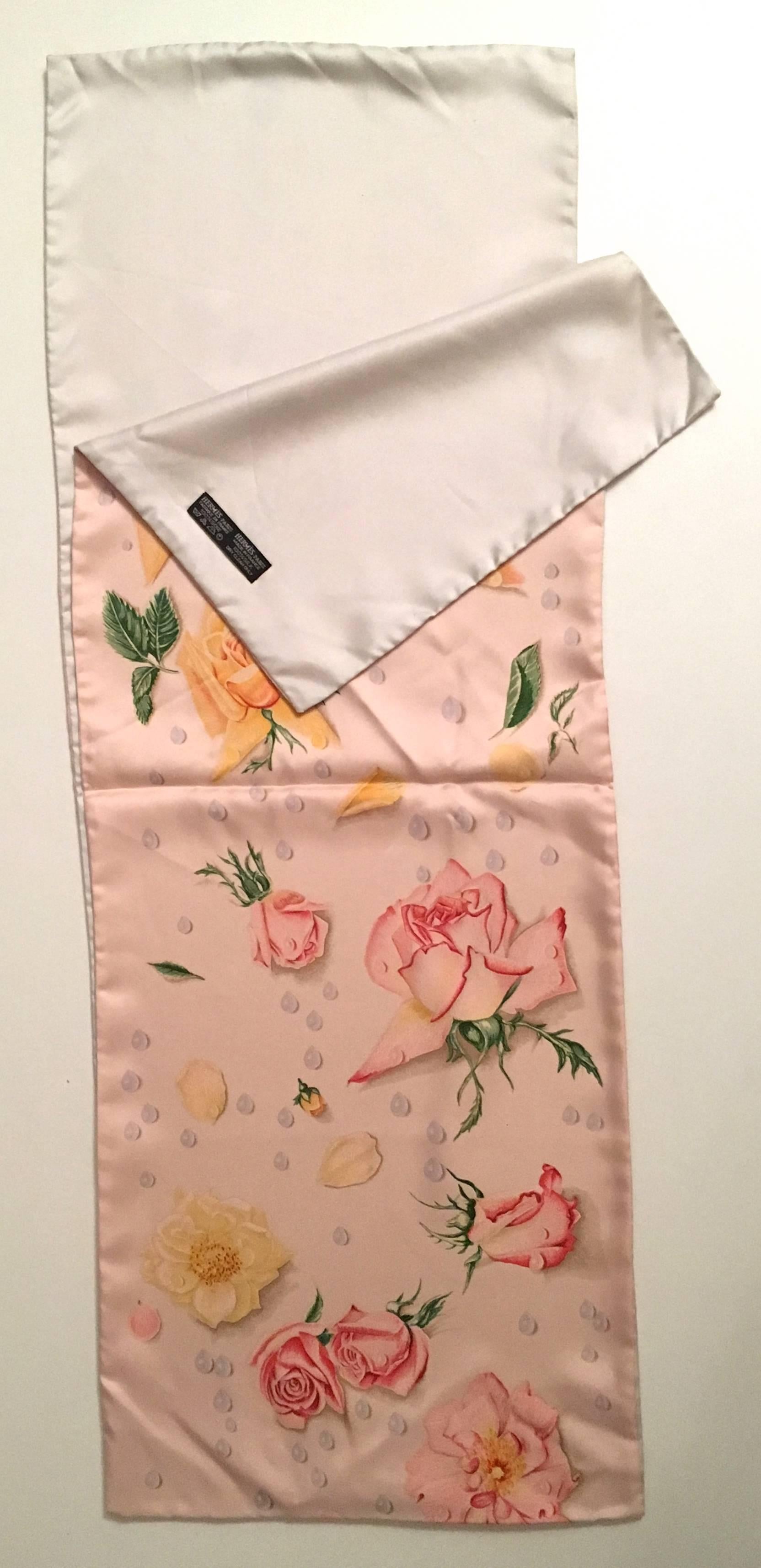 Presented here is a beautiful silk shawl from Hermes Paris. This beautiful shawl / scarf is comprised of two complete connected panels of silk fabric on either side. One side is a light pink floral print and the reverse side of the shawl is a solid