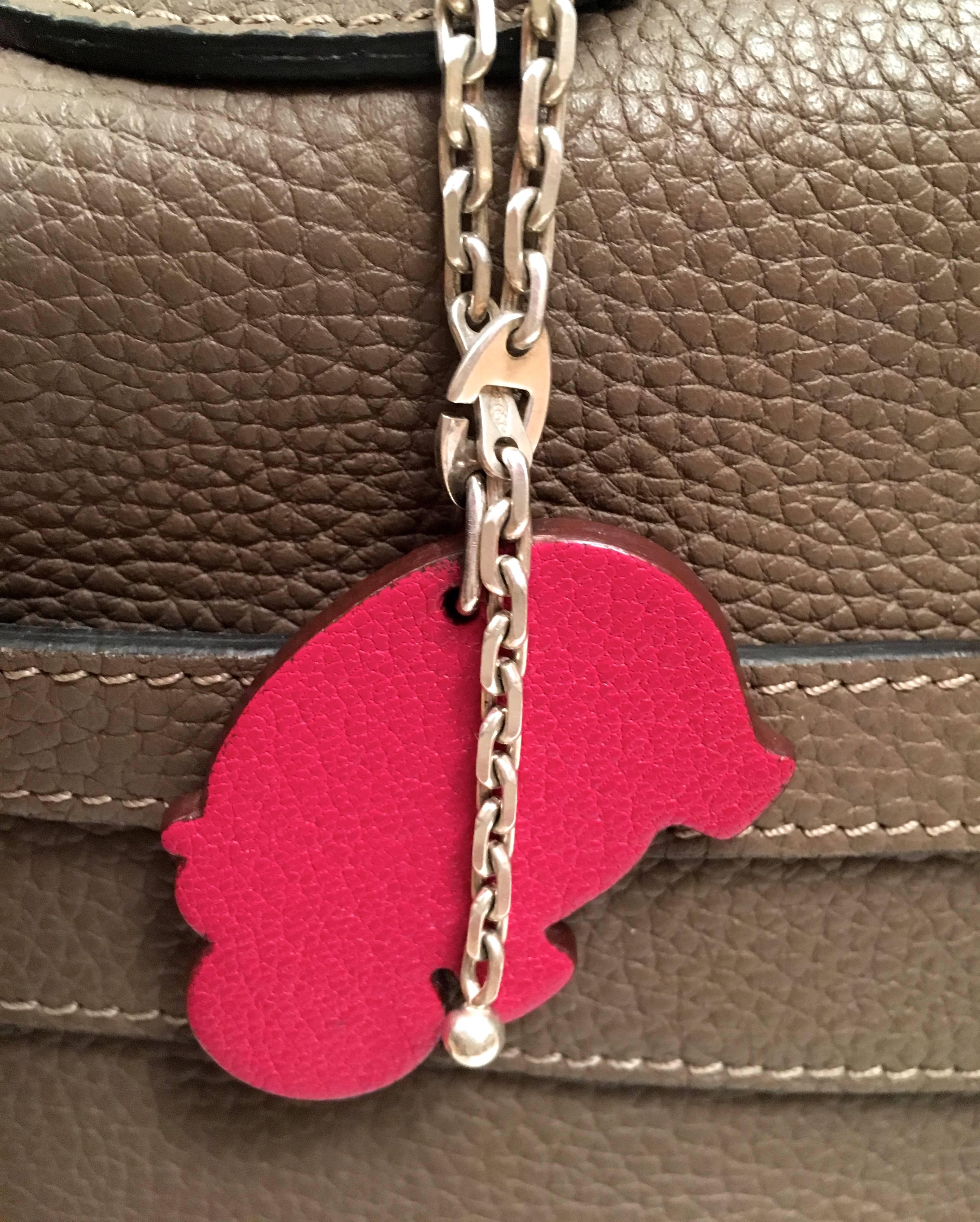 Presented here is a beautiful bag charm from Hermes Paris. This beautiful charm is a hippopotamus shape cut of leather with orange on one side and a magenta on the reverse side. There is a chain that is connected to the charm that is made of .925