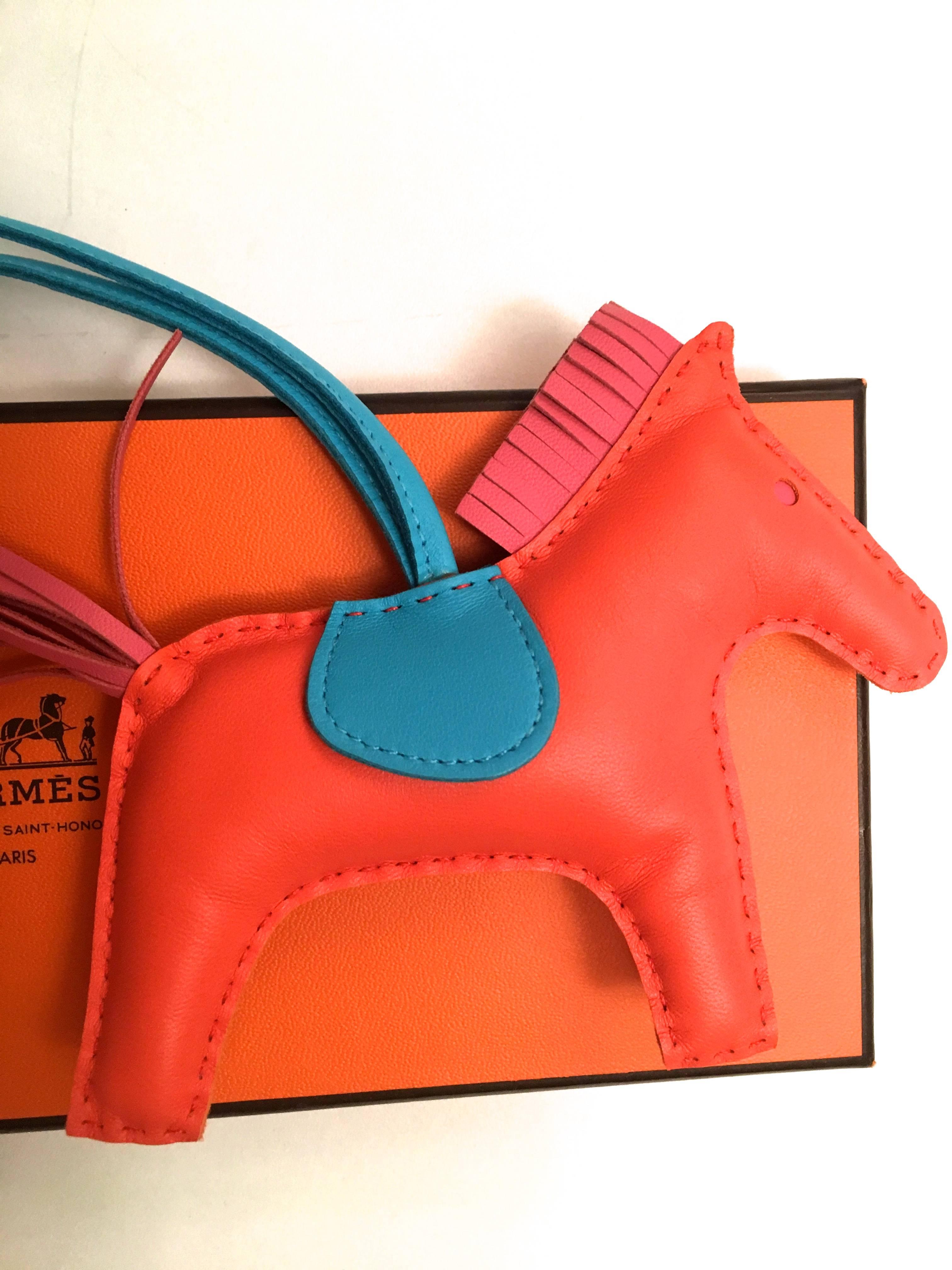 Presented here is a beautiful bag charm from Hermes Paris. This beautiful bag charm is made from butter soft smooth leather. In the Hermes color pallet, the colors of the charm are orange poppy for the main body of the horse, rose azalea for the