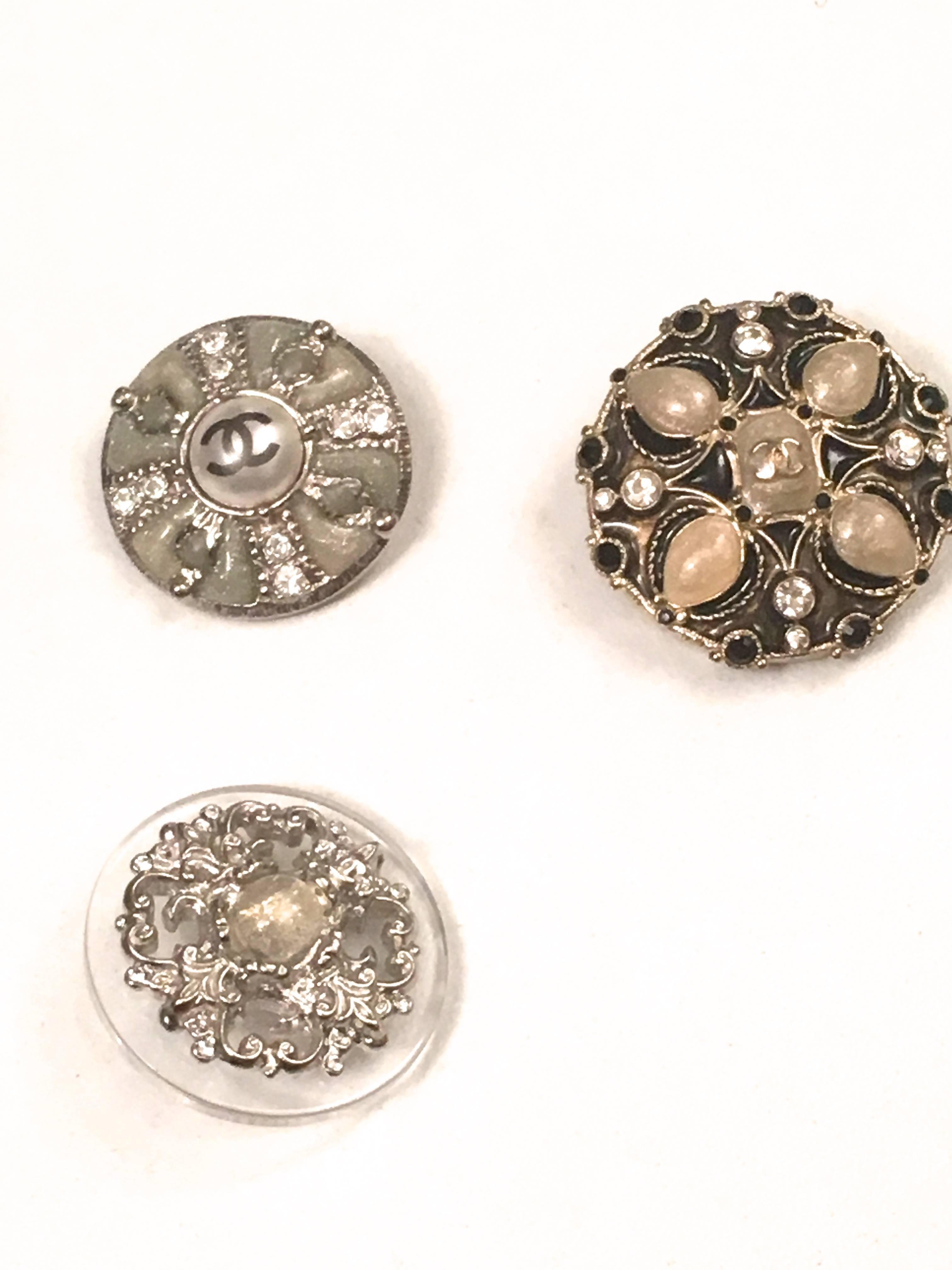 Presented here is an assorted lot of 5 different buttons from Chanel. The buttons are as follows:
 
- 1 button is comprised of faceted green, pink, blue and red rhinestones in a beautiful pattern with a CC logo at the center of the button. All