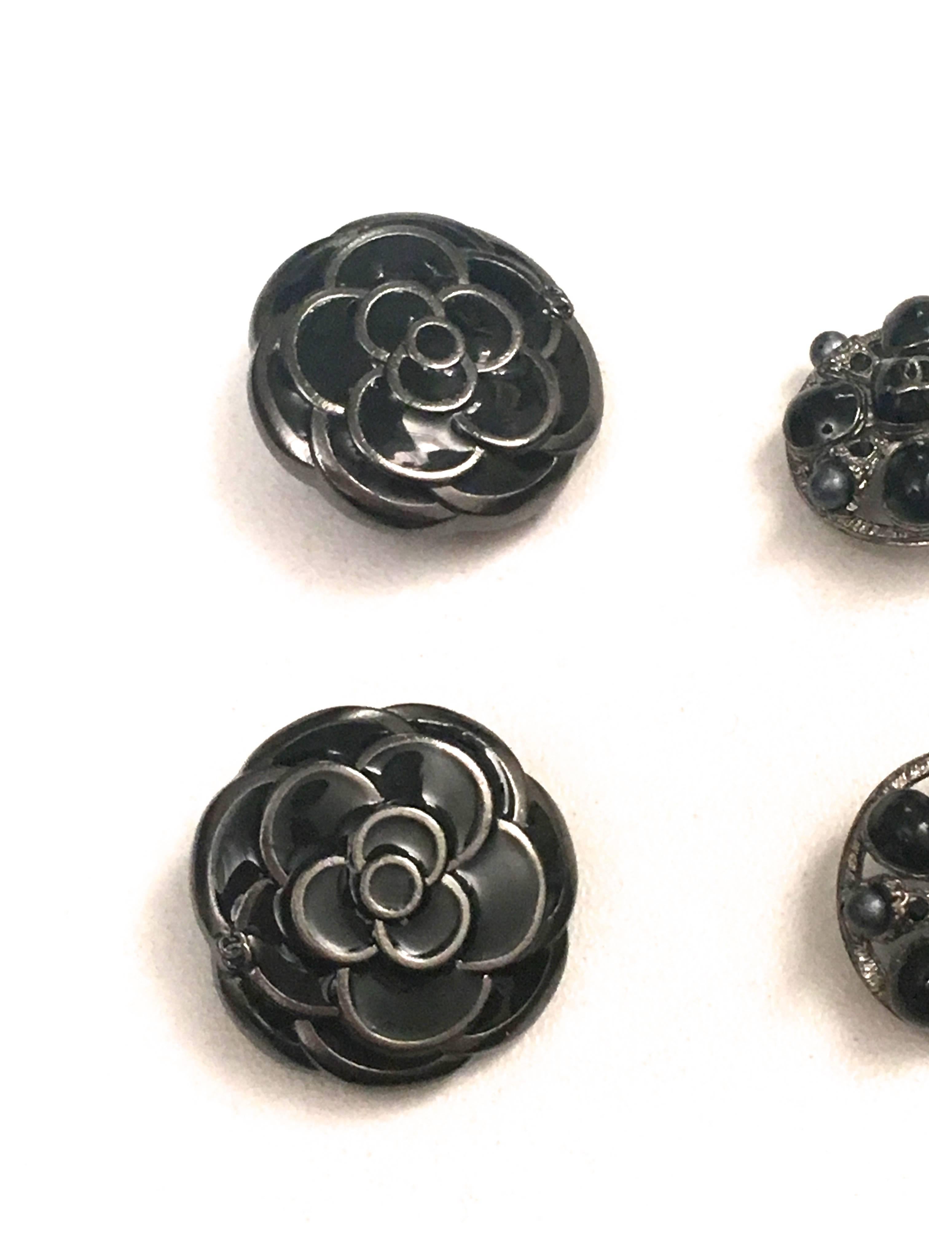 Presented here is a gorgeous assortment of six buttons from Chanel Paris. The buttons are as follows:
- 2 buttons that are silver tone buttons with a gray patina. They have an engraved CC logo at the center of each button front. Around the border of