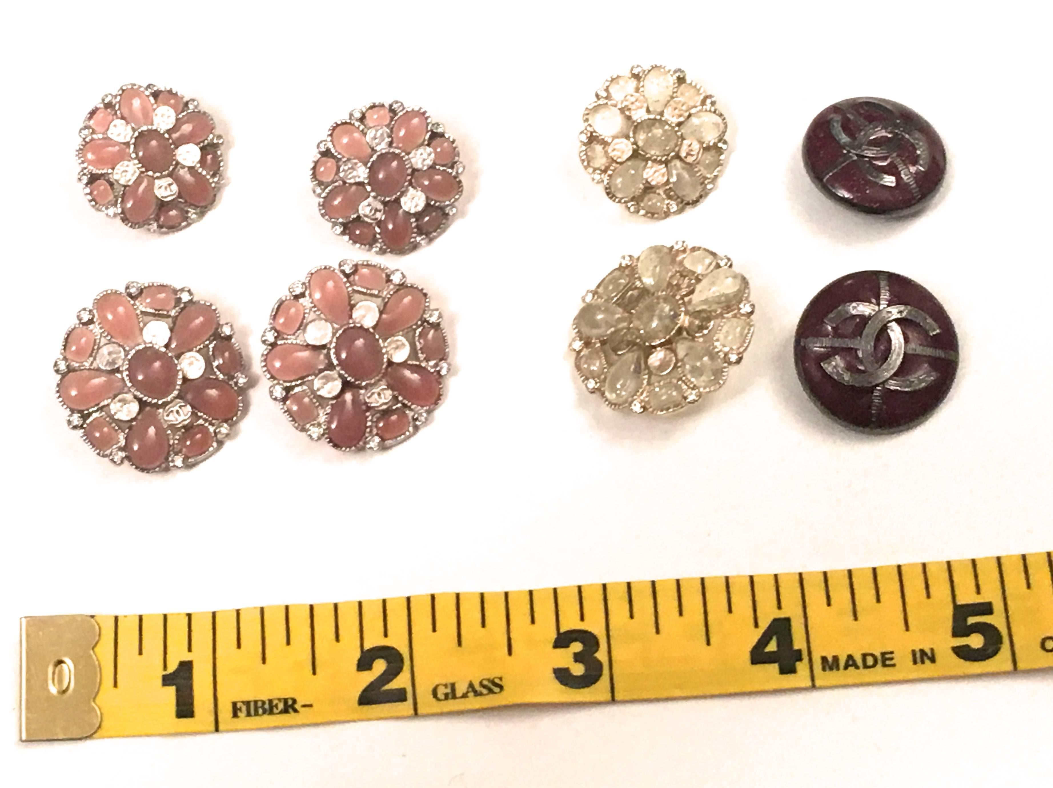 Presented here is a set of 8 assorted buttons from Chanel Paris. The buttons are as follows: 

Four matching buttons that are a composition of a silver tone metal button frame with a pink gripouix throughout and small circles with the cc mark. Two