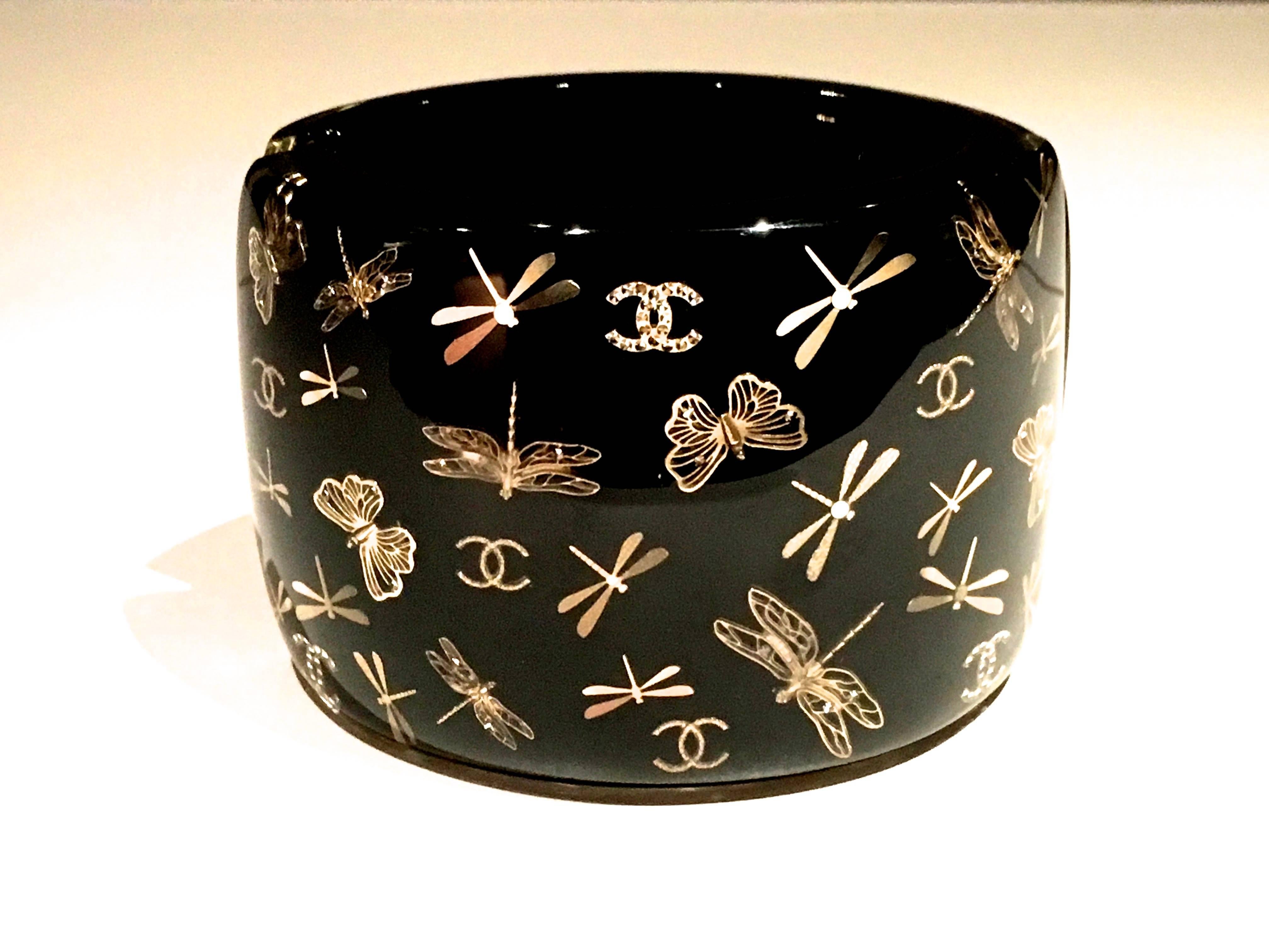 Presented here is a stunning lucite cuff bracelet from Chanel. The magnificent bracelet is made of a combination of black and translucent lucite. Inside the translucent lucite, there are gold tone charms of dragonflies, butterflies and the iconic