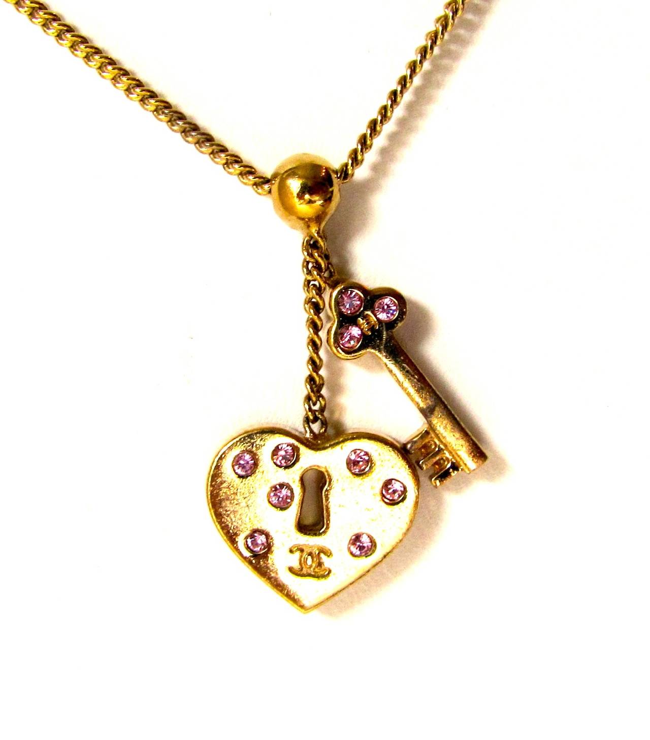 Beautiful Chanel necklace. Gold tone chain with two charms: A key and a heart charm with pink crystals encrusted to the surface on both sides of the charm. The heart also has the CC logo engraved upon the surface of the charm. Beautiful necklace
