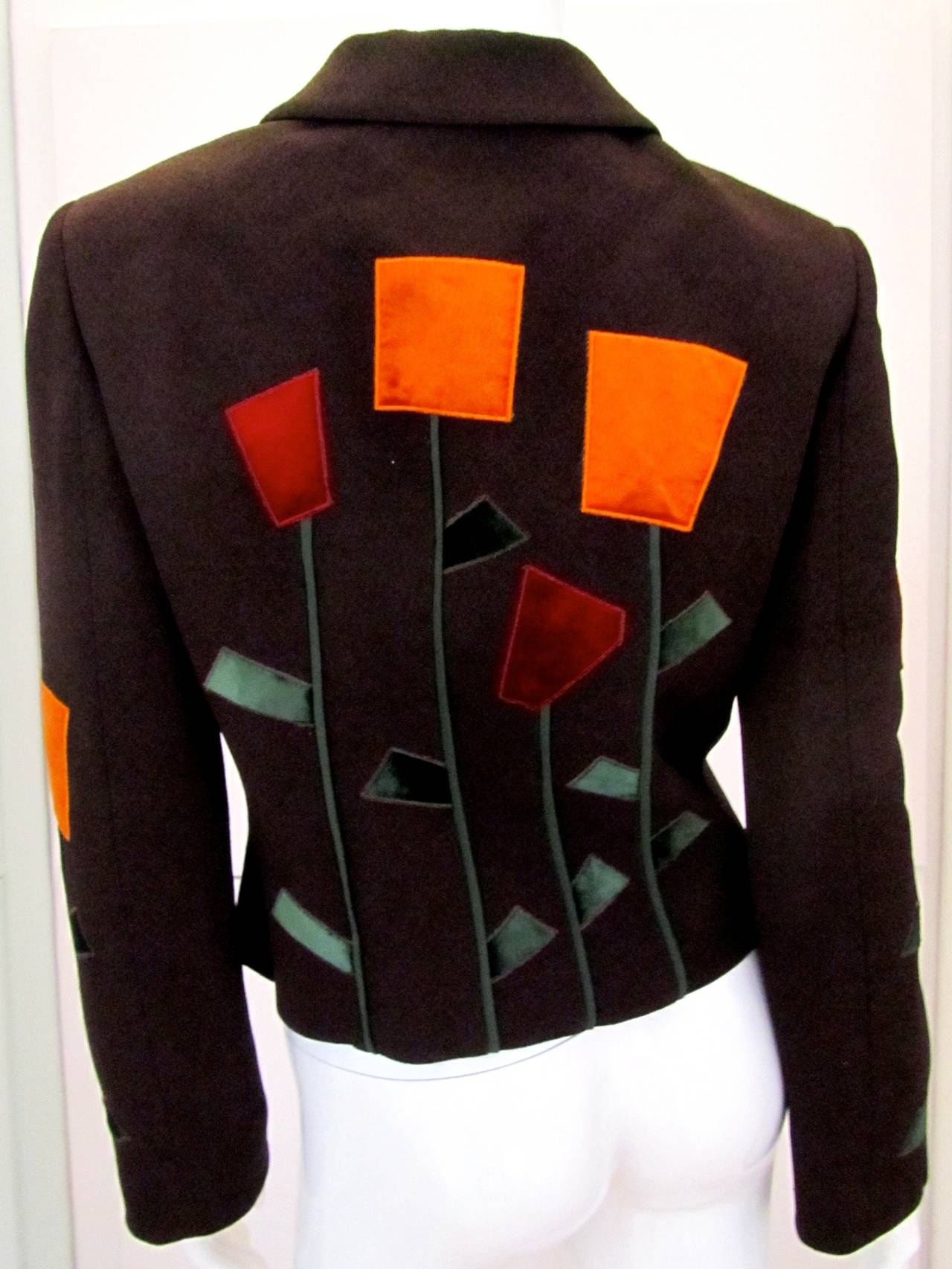 Moschino Cheap and Chic blazer with geometric flower design. The blazer is 75% rayon and 25% wool. The flowers are a soft shiny velvet and are orange, red, and green. Jacket is in excellent condition and is a magnificent example of Moschino's design