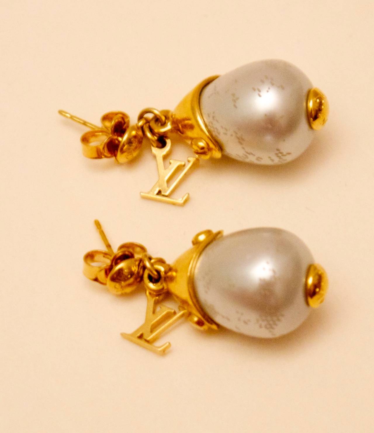 Louis Vuitton pearl tear drop shaped earrings. They also each have a gold tone charm on each with the iconic LV logo charm. Gorgeous pair of earrings that are versatile for both informal and formal occasions. Excellent piece to add to any personal