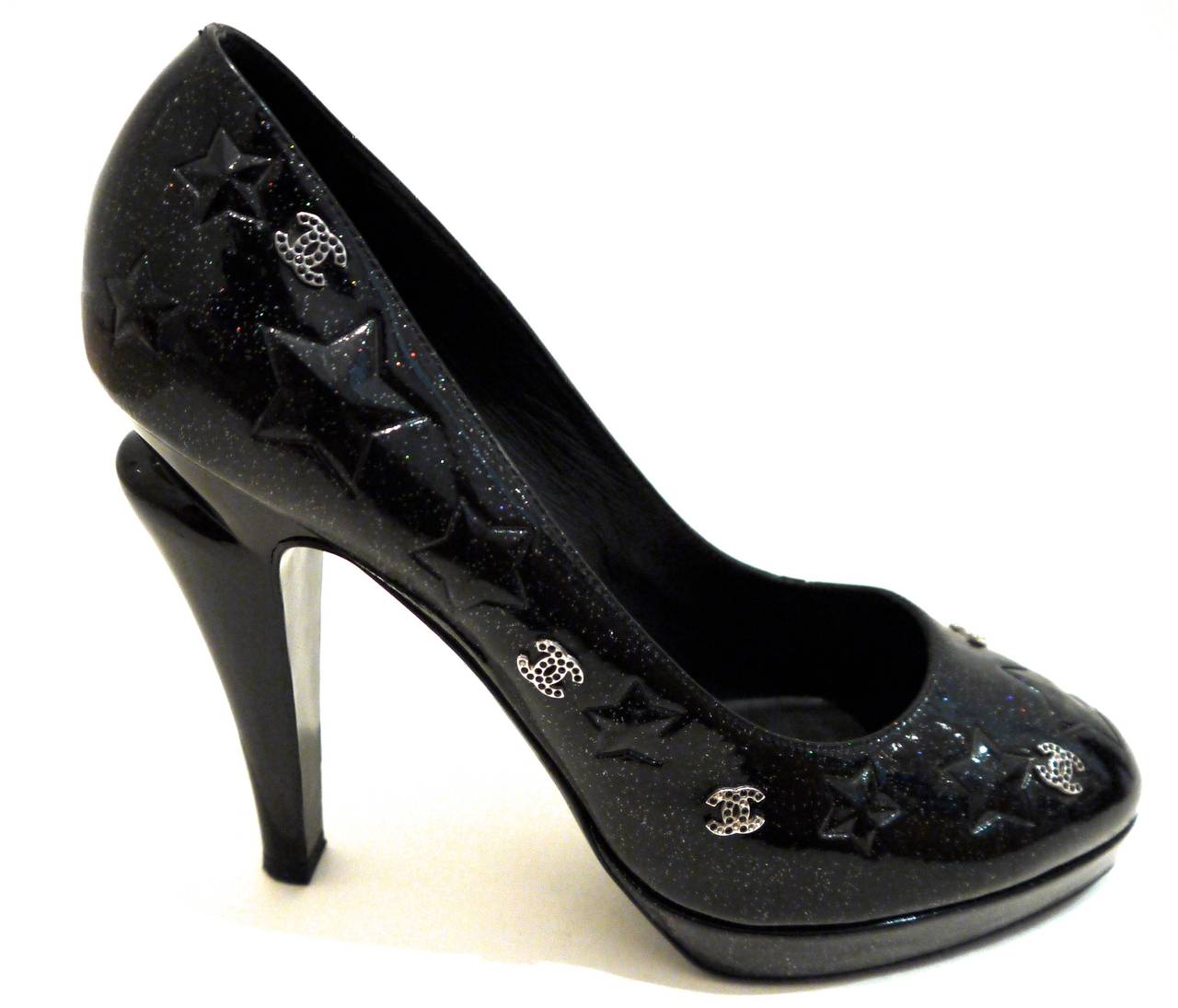 These beautiful Chanel shoes consist of a black patent leather with silver sparkles embedded inside of the leather surrounded by imprinted stars and CC logos with black stones in the logo. These beautiful platform shoes are size 41. They were worn