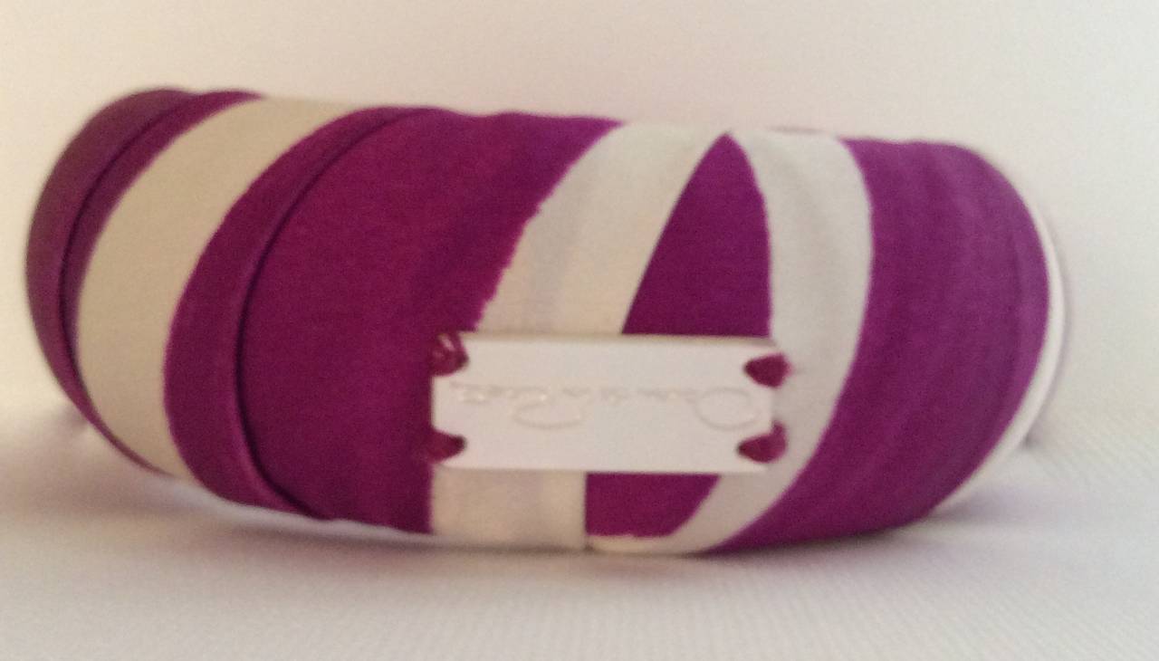 This new Oscar de la Renta bracelet is made of wrapped purple and cream silk and features 'Oscar de la Renta' written out in a mother of pearl logo. The diameter of the bracelet is 2.75 inches and it is 1.75 inches thick.