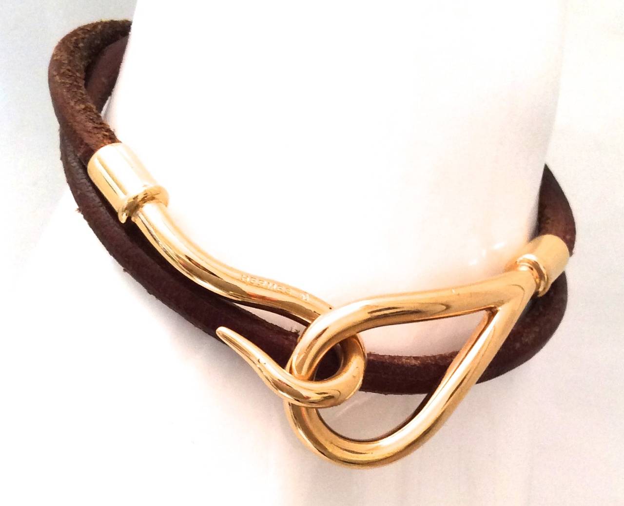 This gold tone and brown leather Hermes Necklace can be used as a bracelet or necklace. It consist of brown leather connected to an oval shape gold-tone holder which connects to the hook. When wrapped around twice it can be used as bracelet.