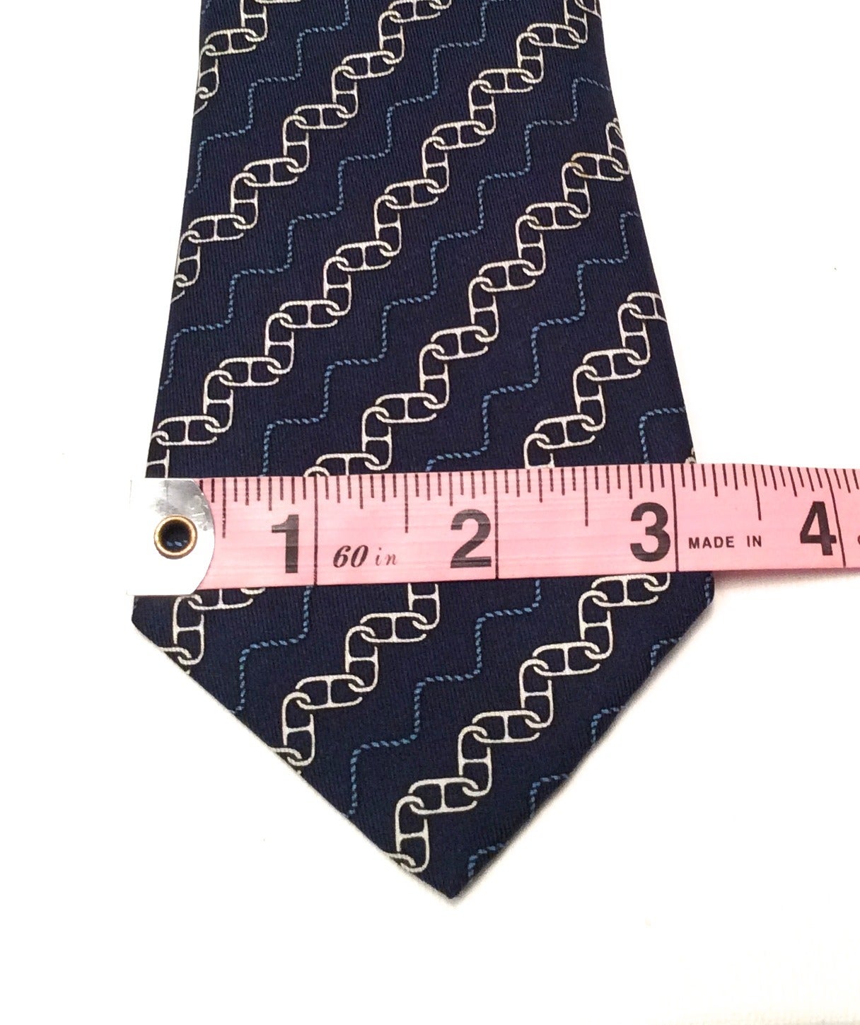 Hermes Silk Necktie that is made up of blue, black, and silver colors. There is a series of chain links patterned in a diagonal form along the length of the tie.