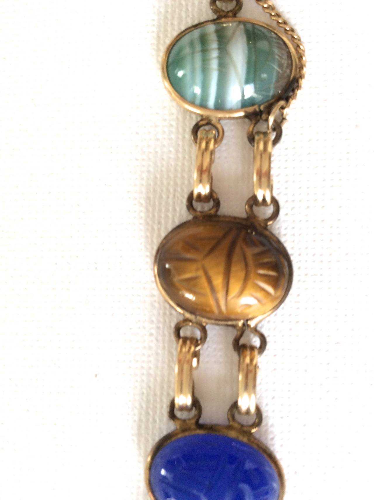 A vintage scarab stone bracelet from the 1970's.  The bracelet is an Egyptian Revival bracelet that is a composition of gold fill chain with genuine   scarab stones, including Jasper, Lapis, Jade, and Tigers Eye.  . Each scarab has individual