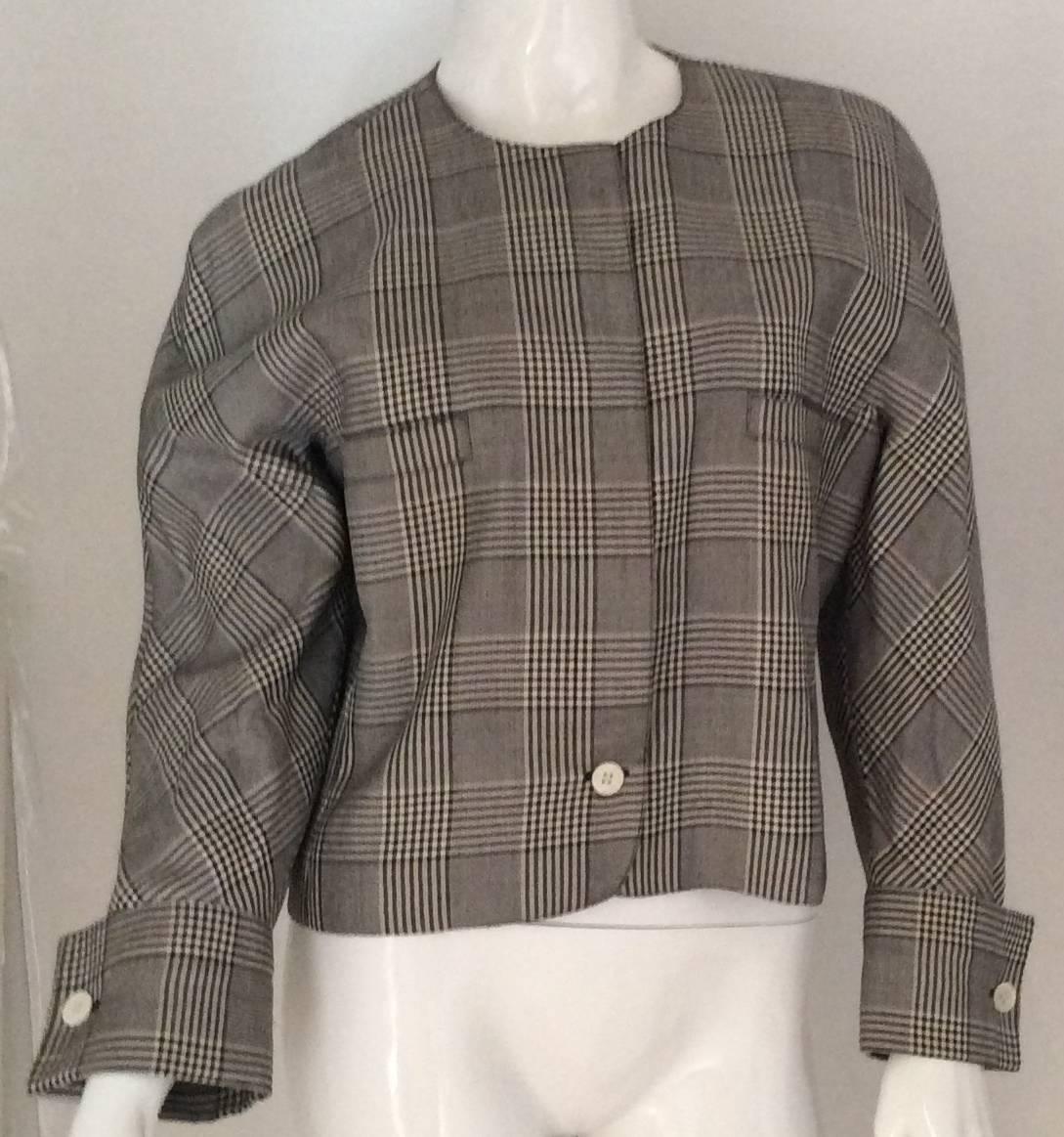 Genny was one of the leading manufacturers in the 1980's of quality, simple, tasteful and well cut clothing. This beautiful black and white houndstooth jacket is no exception. It has 5 white buttons up the front of the sleeve and two cuffed arms.