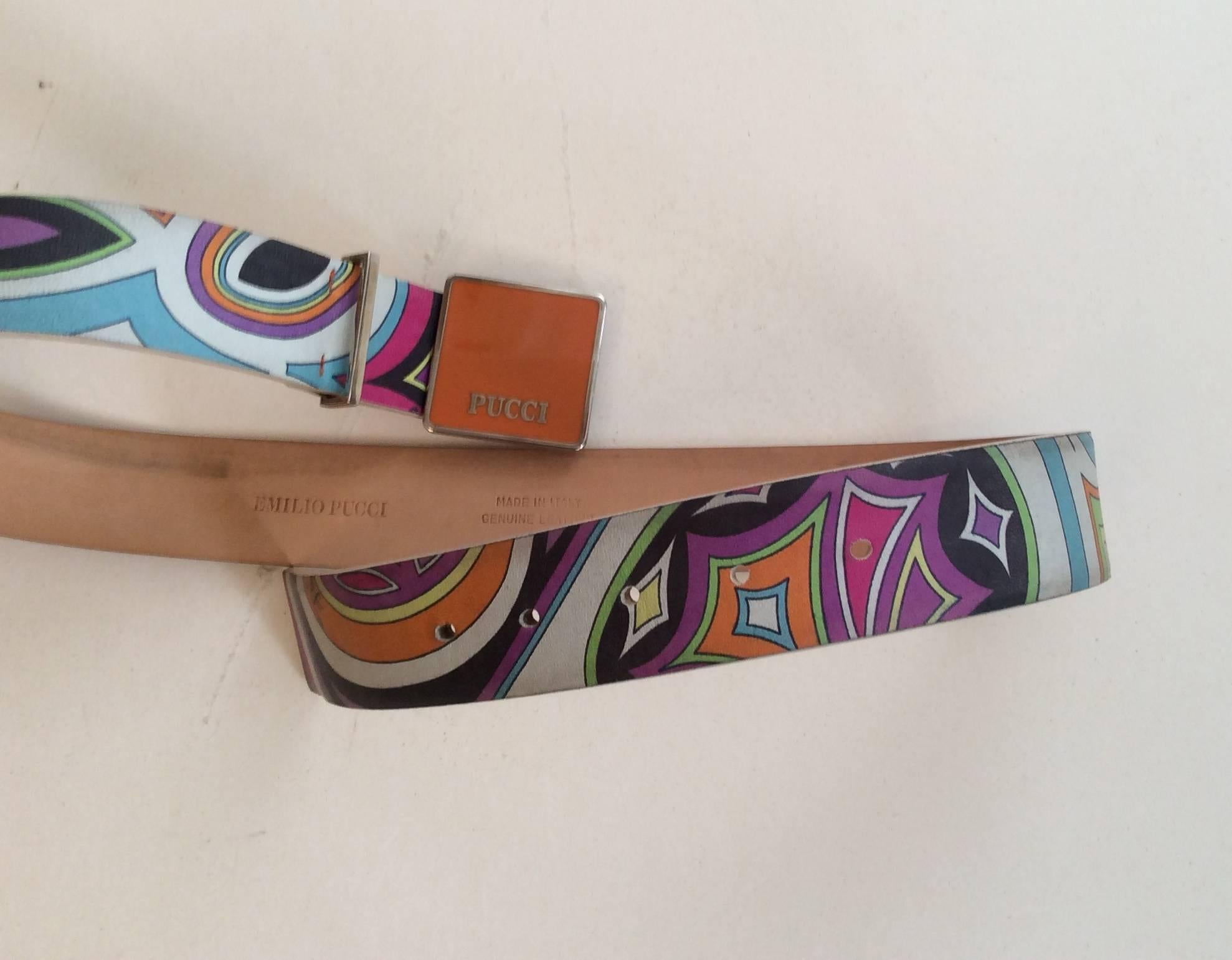 This Emilio Pucci leather belt is a size 75 that is adjustable and has a metal and enamel orange buckle. The belt has a gorgeous ornate pattern that is classically Pucci in colors of black, lime green, orange, light blue, purple, and pink. A