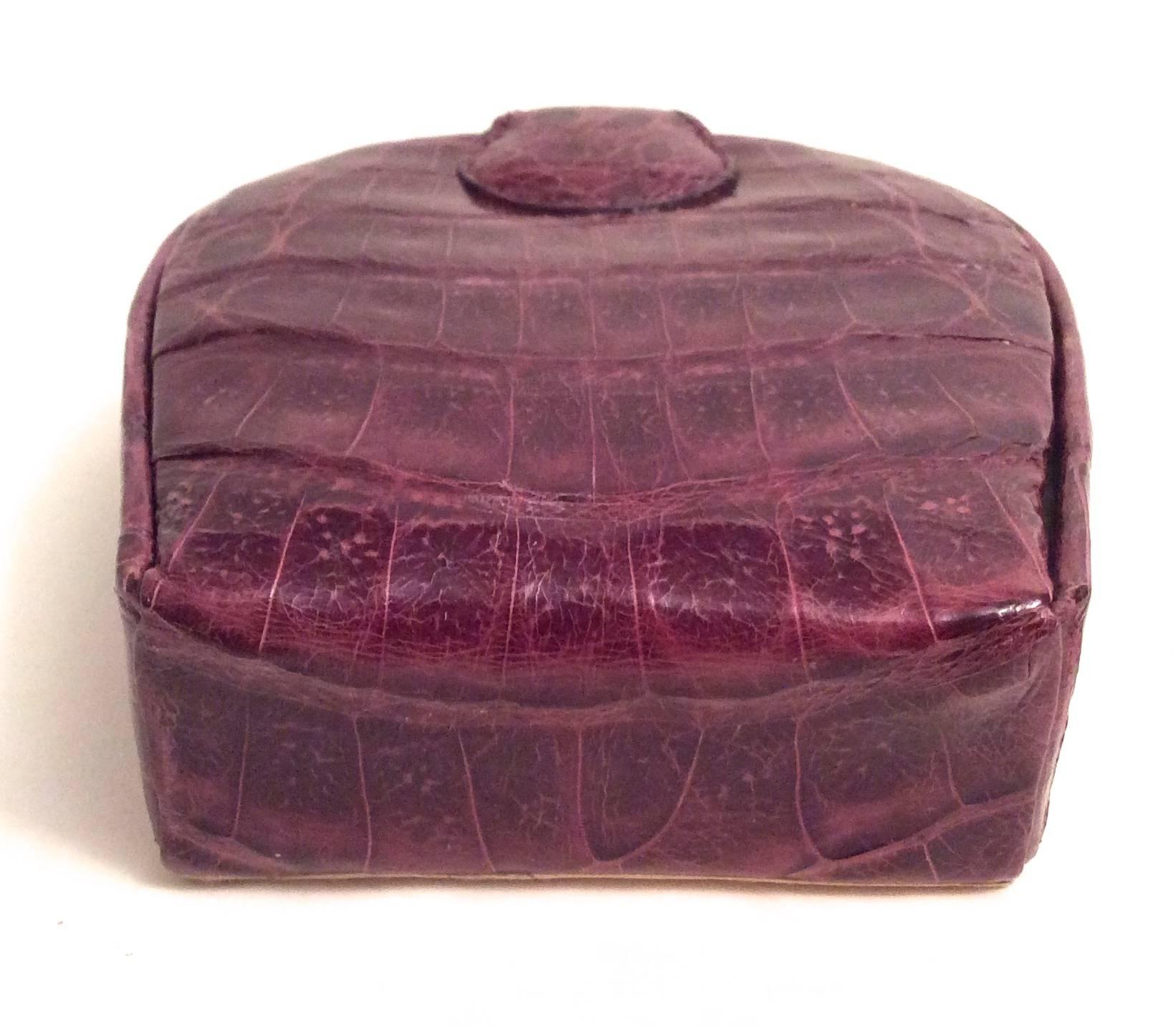 Here is a remarkably crafted alligator case that is excellent for holding small jewelry or other small objects. It is beautifully crafted in crocodile skin and is purple on the exterior with a soft beige leather on the interior. There is an insert