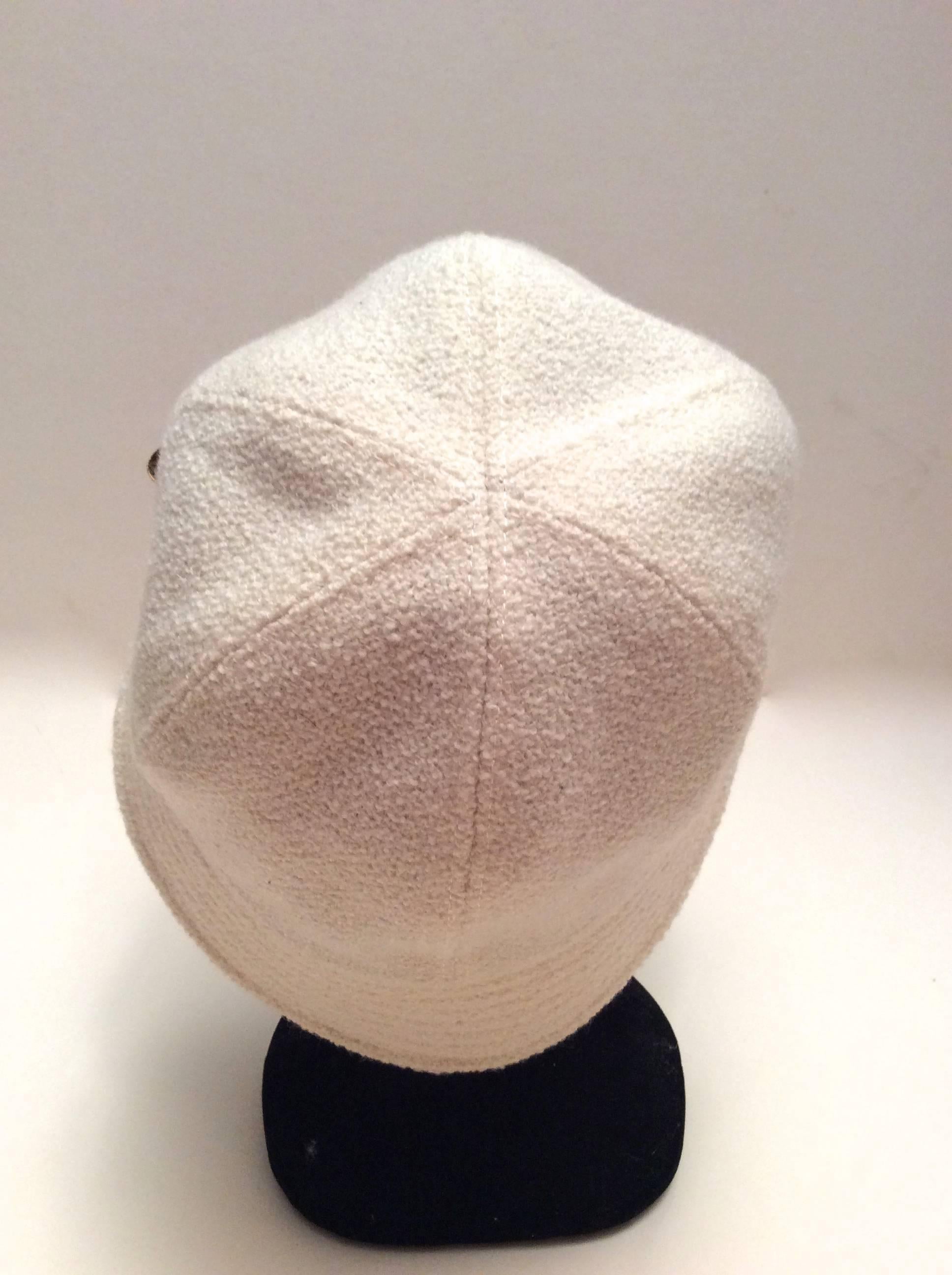 Chanel white boucle hat with gold tone metal camellia flower emblem. Gorgeous hat that is versatile for varying occasions. The size is a 58 and is in excellent condition. Magnificent addition to any personal clothing wardrobe. 

The interior of