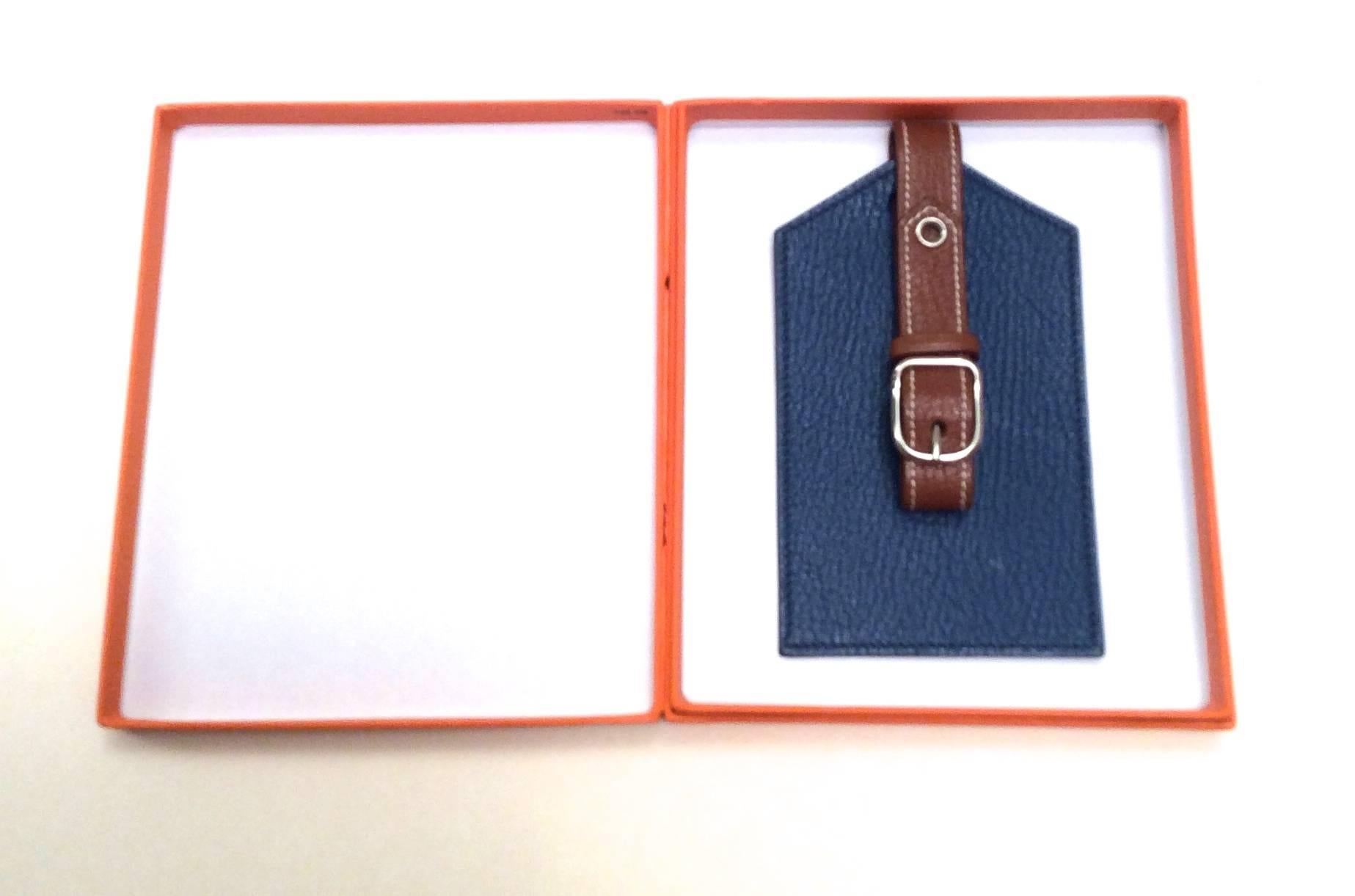 This Hermes luggage tag / bag charm is new and is a blue tag with a brown strap. It is a remarkable addition to any personal luggage collection or handbag collection. Tag has a silver buckle for opening and closing the strap.

Dimensions of