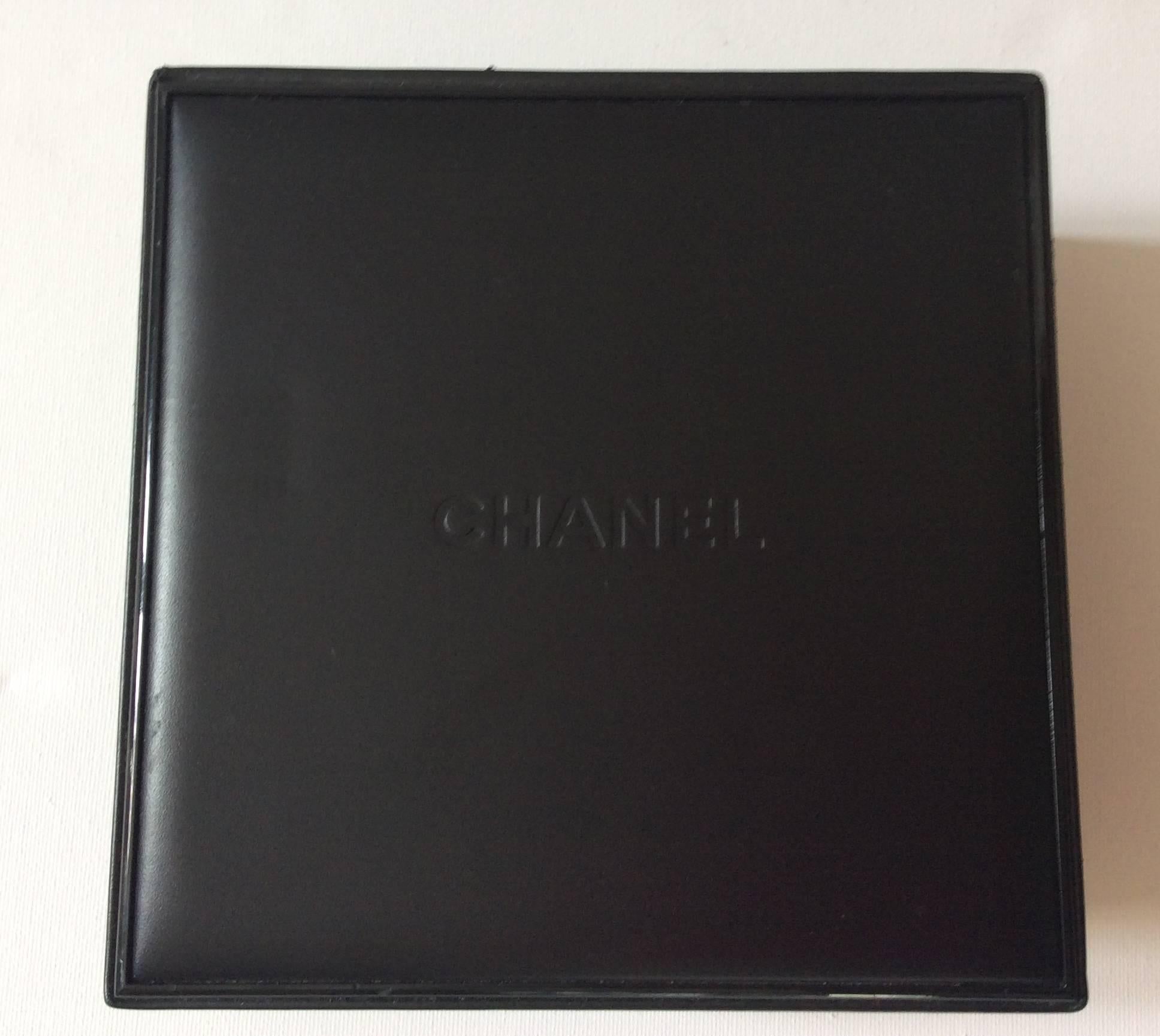 This Chanel fine jewelry box is black and is embossed with the Chanel name on the top of the box. It is an extremely uncommon box to find. The box is square and is lined entirely in suede leather. The inside of the box is also embossed with the