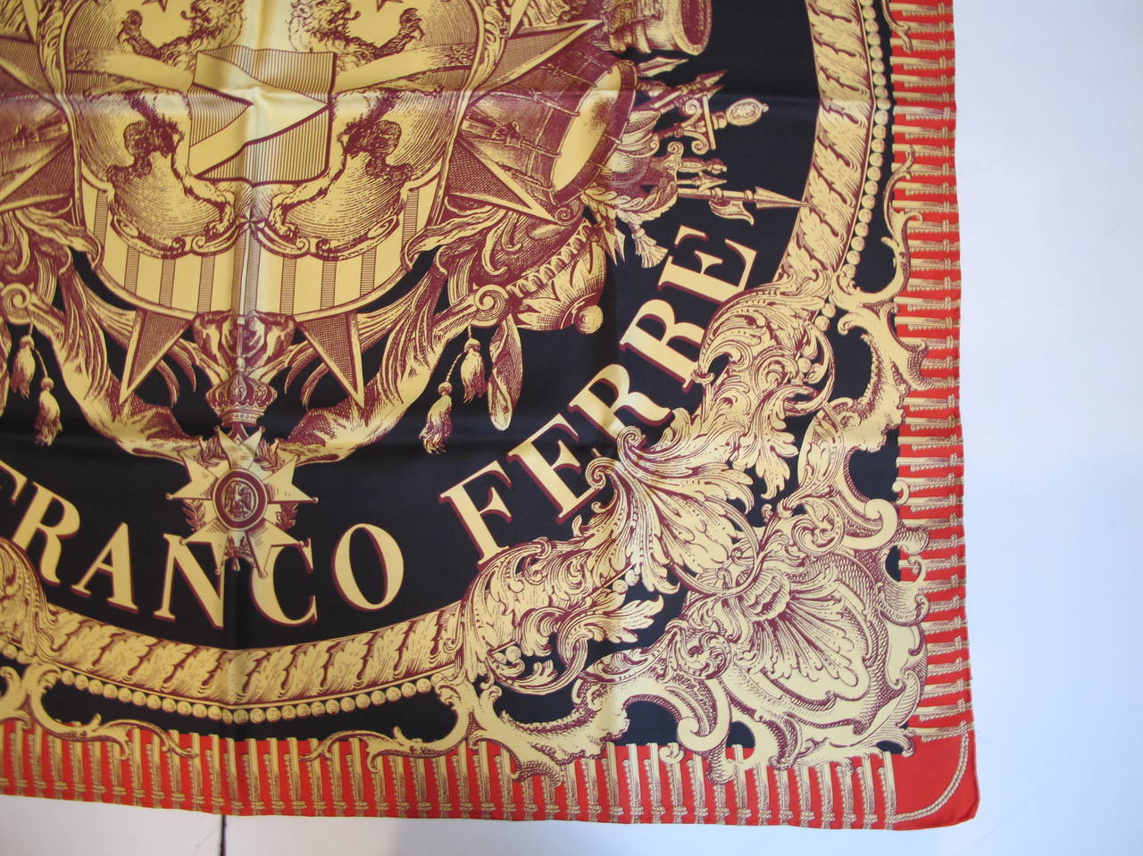 Gianfranco Ferre silk scarf with rolled hem created when he was at the height of his career. The majestic crown motif is protected by ferocious lions. The fantastical emblematic realm is brought to life via its colors of black, rich red and precious